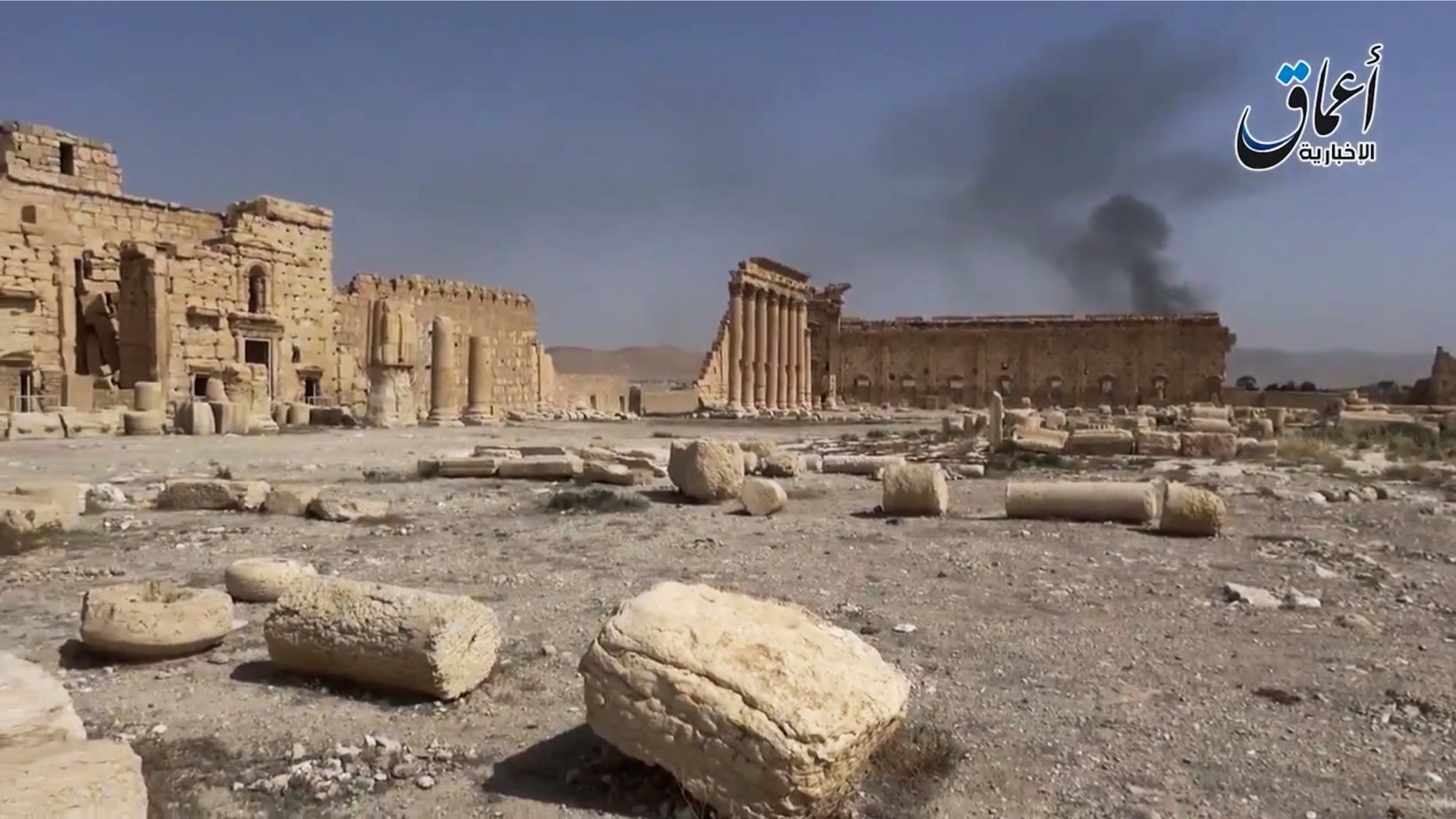 In this image made from a militant video posted on YouTube on May 26, 2015, which has been verified and is consistent with other AP reporting, smoke rises behind archaeological ruins in Palmyra, Syria. The video released by a media arm of the Islamic State group purportedly showed the archaeological ruins of Palmyra apparently undamaged.
