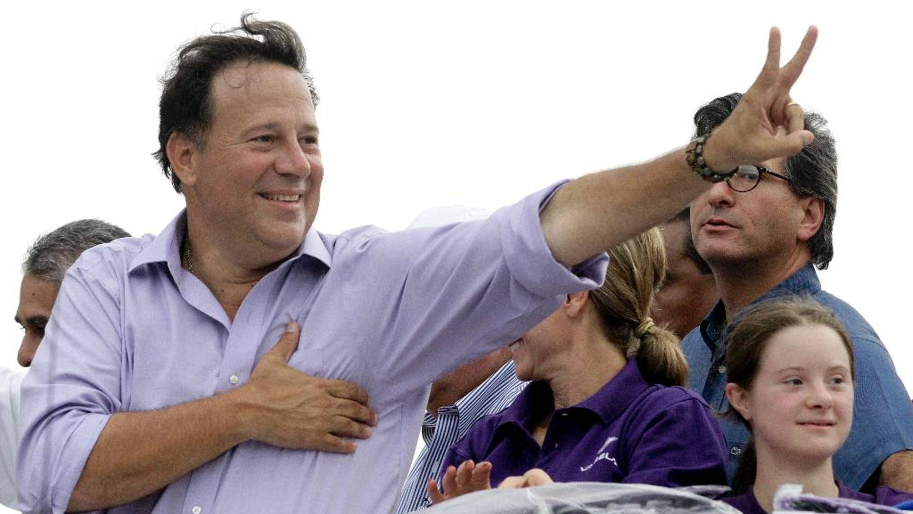 FILE- In this April 25, 2014 file photo, Juan Carlos Varela, presidential candidate for the Panamenista Party, waves to supporters during a campaign caravan through Arraijan on the outskirts of Panama City. Varela owes a debt of gratitude to a former adviser to John McCain’s ill-fated 2008 White House run for his come from behind victory in Panama’s presidential election. (AP Photo/Arnulfo Franco, File)