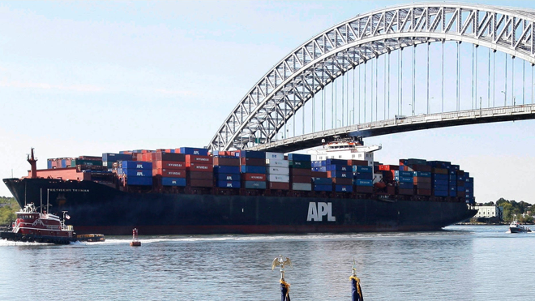 FILE - In this Tuesday, Sept. 21, 2010 file photo, the President Truman, a large cargo ship, passes under the Bayonne Bridge in Bayonne, N.J., as New Jersey Gov. Chris Christie, third left, front, and Lt. Gov. Kim Guadagno, fourth left, front, listen with others, as U.S. Rep. Albio Sires (D-NJ) talks about plans to raise the height of the bridge to accommodate the larger next generation of cargo ships. Residents in N.J. cities and towns are leery of the monster ships that will soon arrive because of a trade project thousands of miles away they believe will harm their air quality, roadways and waterways.  (AP Photo/Mel Evans,file)