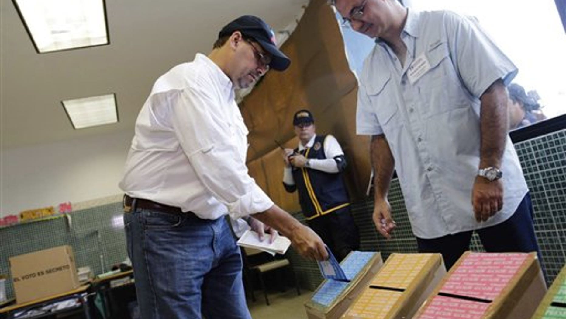 Jose Domingo Arias, left, presidential candidate for the Democratic Change Party, casts his ballots at a polling station in Panama City, Sunday, May 4, 2014. Panamanians are choosing President Ricardo Martinelli's successor in a three-way dogfight marked more by ugly personality clashes than any deep disagreements over the way forward for Latin America's standout economy. (AP Photo/Tito Herrera)