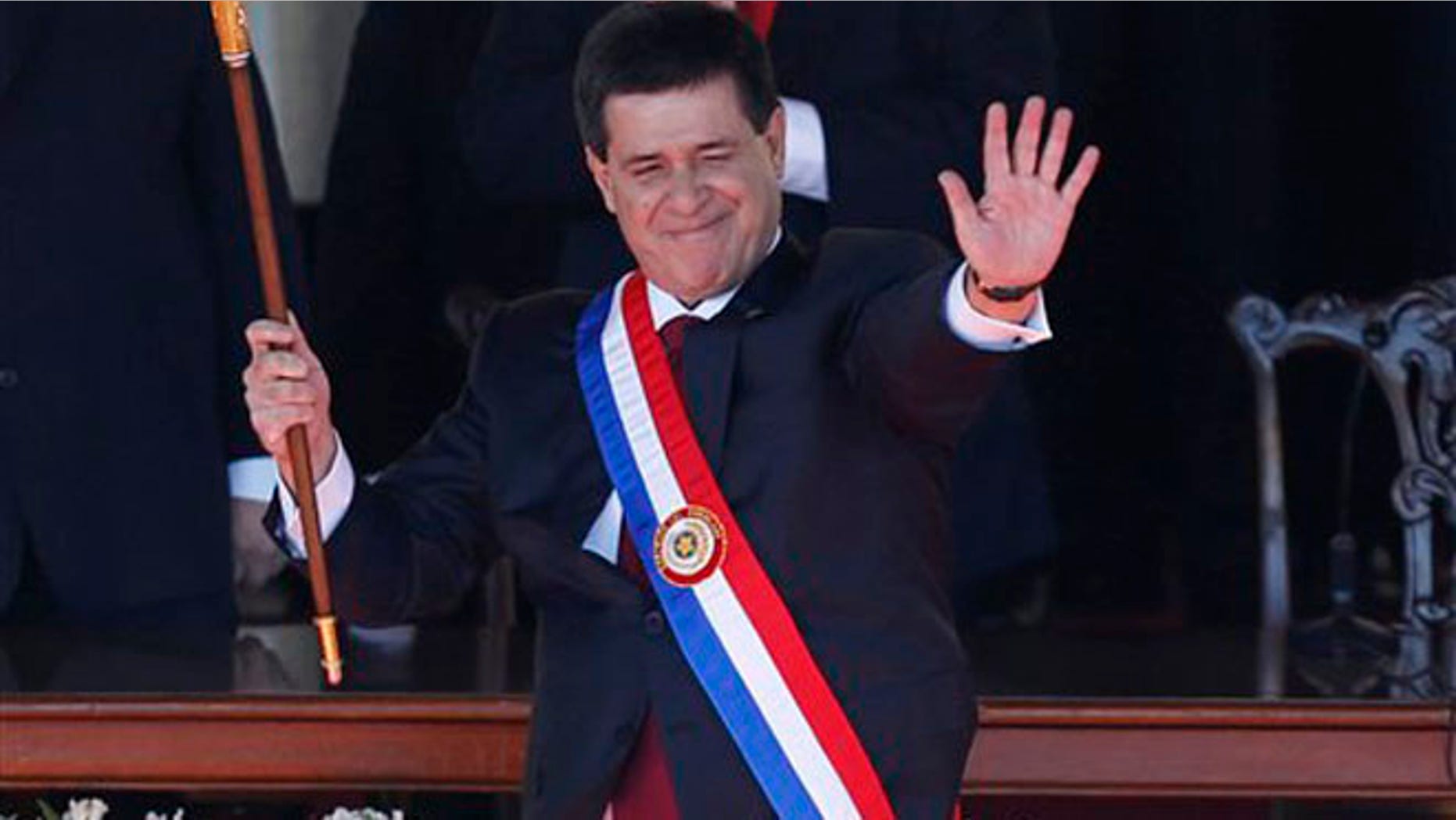 Paraguay's New President Horacio Cartes waves holding the presidential baton and wearing the presidential sash during his swearing-in ceremony at Palacio de Lopez presidential palace in Asuncion, Paraguay, Thursday, Aug. 15, 2013.