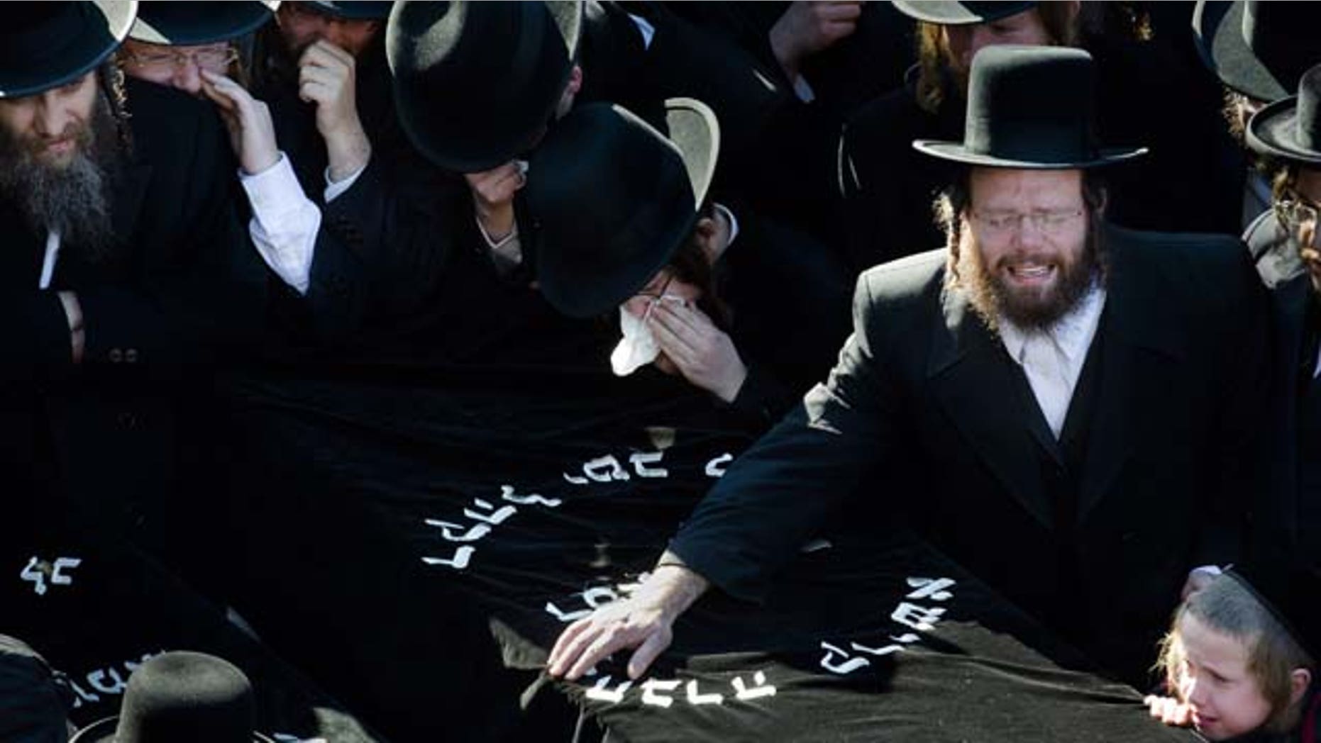 March 3, 2013: Members of the Satmar Orthodox Jewish community grieve over the coffins at the funeral for two expectant parents who were killed in a car accident.