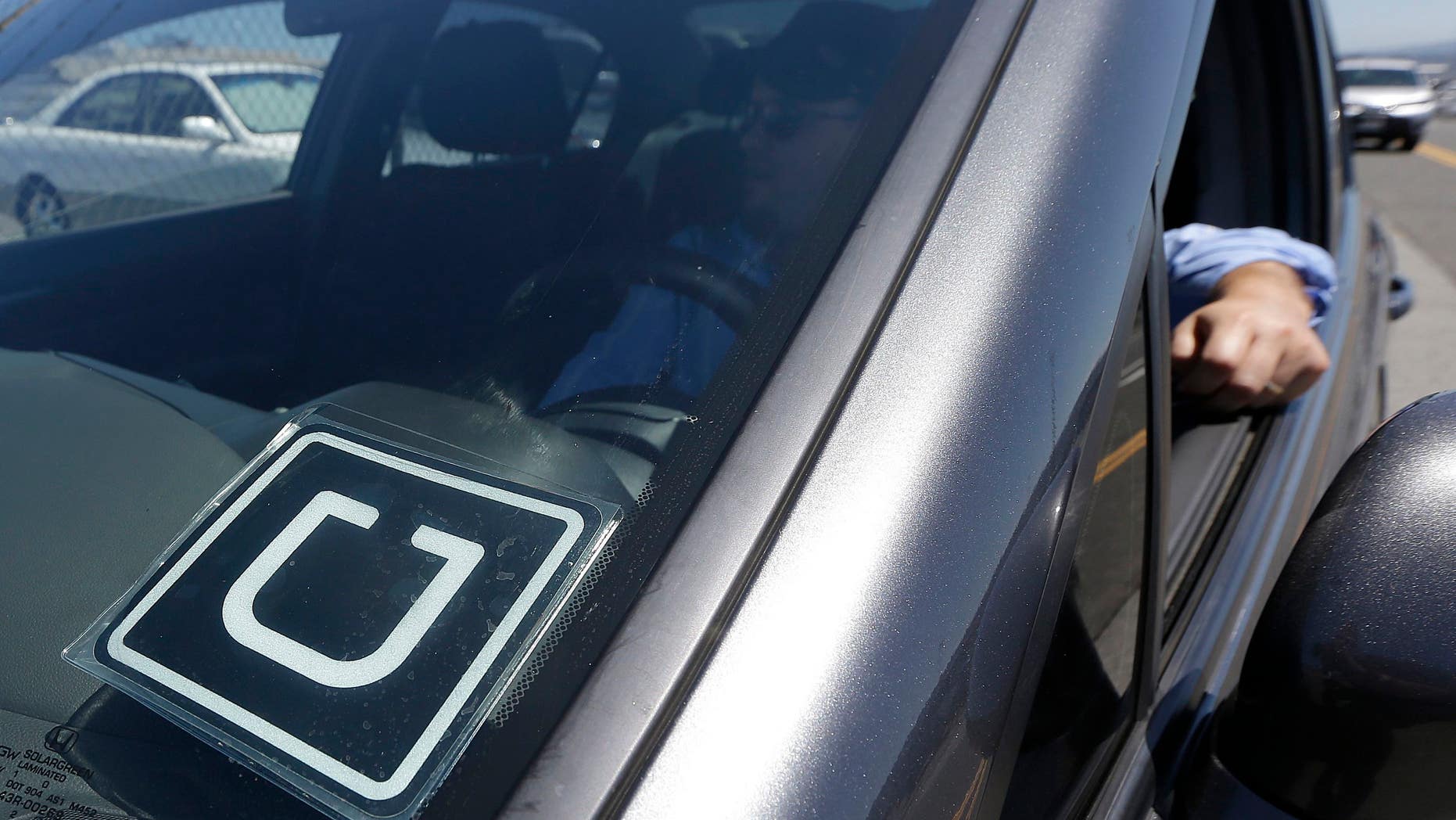 An Uber driver sits in his car parked near the San Francisco International Airport.
