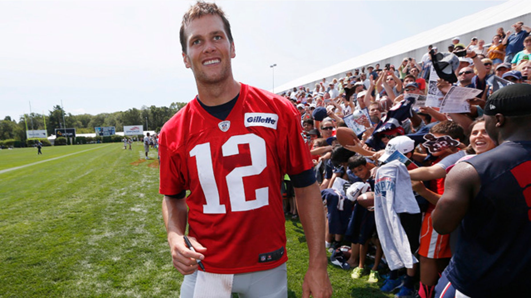 Aug. 1, 2015: New England Patriots quarterback Tom Brady walks down the line of fans signing autographs during an NFL football training camp in Foxborough, Mass. (AP Photo/Michael Dwyer)