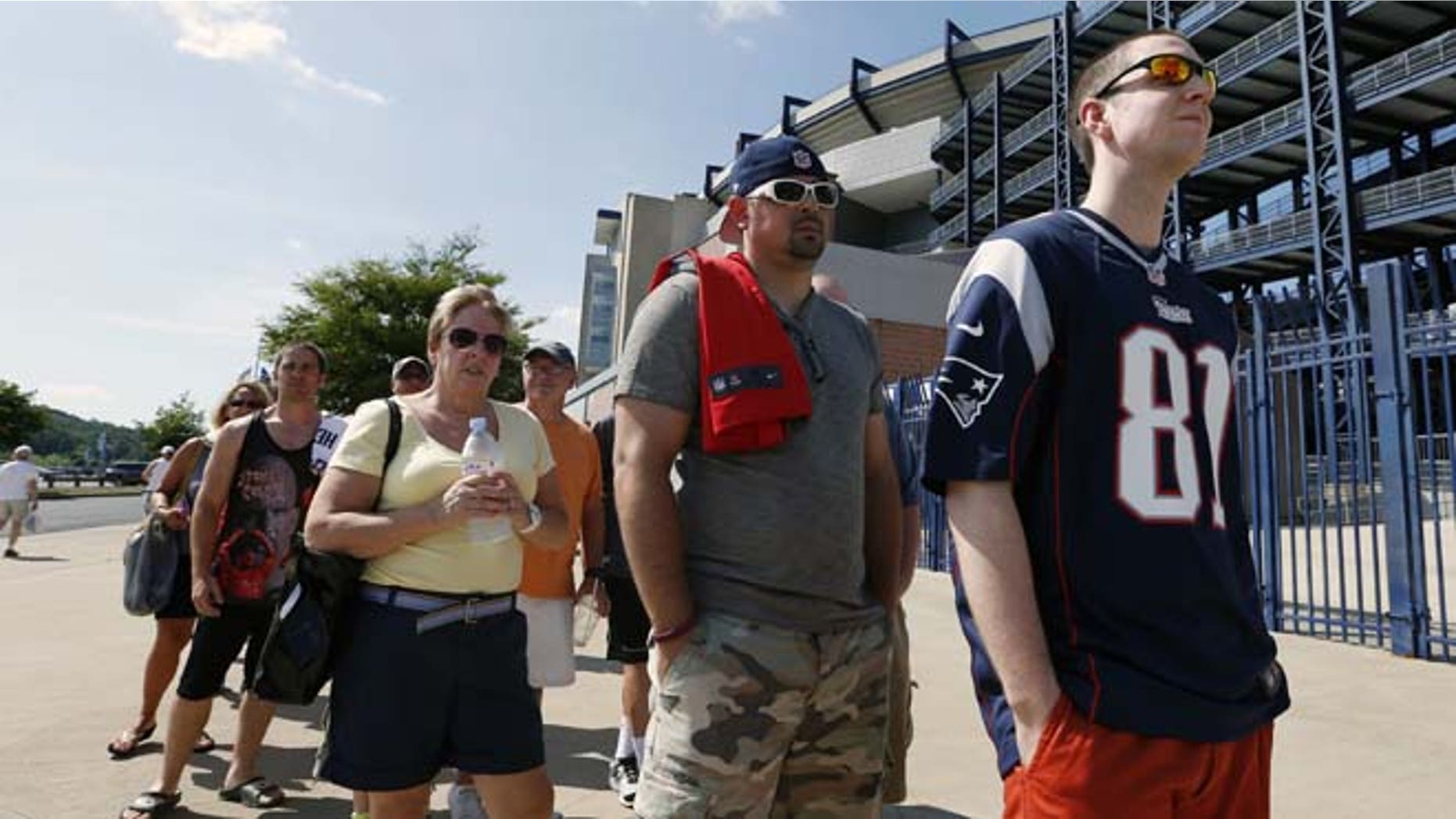 July 6, 2013: Mike Davies, right, of Norfolk, Mass., wears his New England Patriots Aaron Hernandez football jersey one last time while waiting in an exchange line outside Gillette Stadium in Foxborough, Mass. Fans may trade an Aaron Hernandez jersey with his name on it they purchased for one of another player on the NFL team. The team released Hernandez after he was arrested for allegedly orchestrating the death of Odin Lloyd.