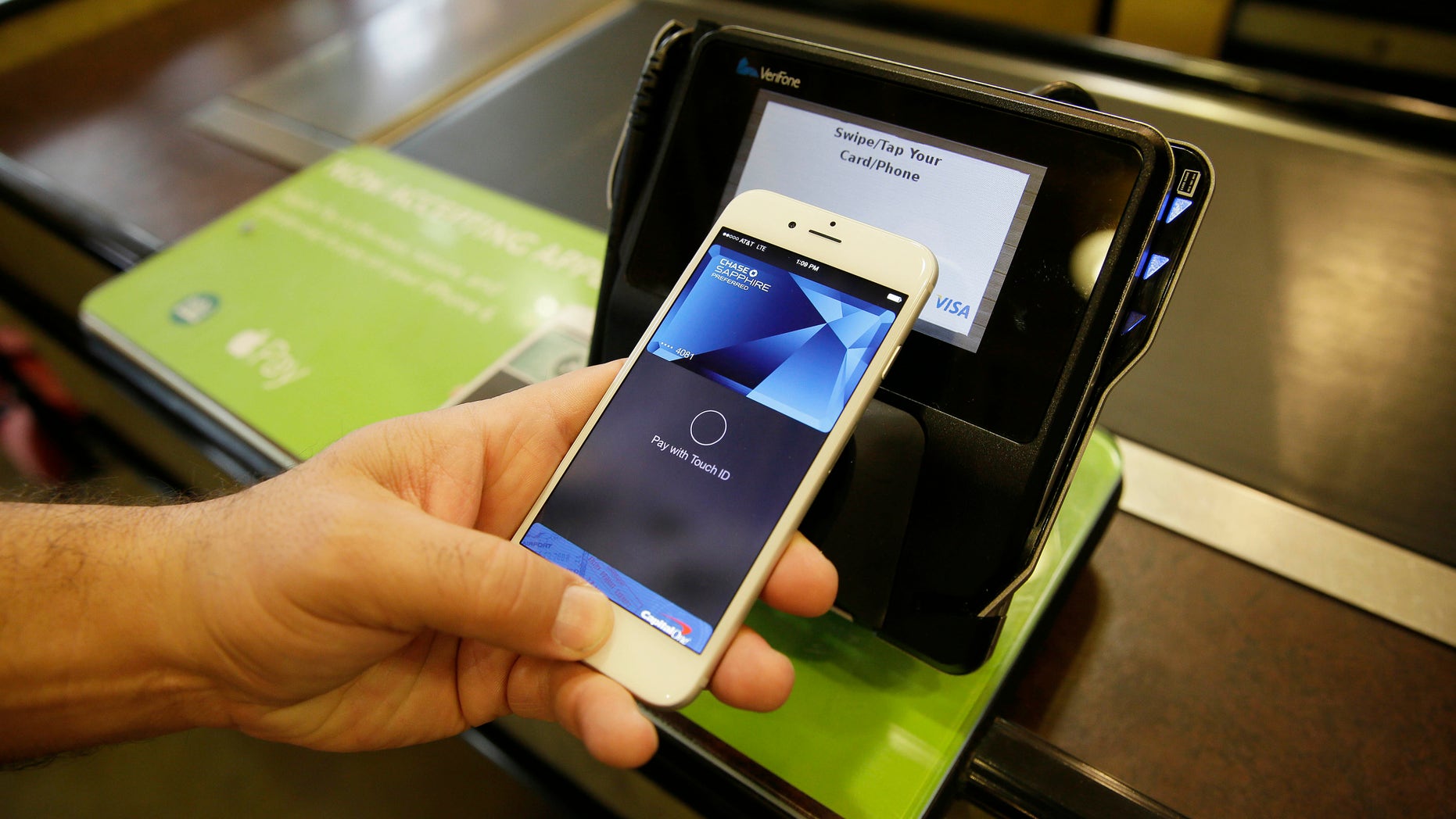 In this photo taken Friday, Oct. 17, 2014, Eddy Cue, Apple Senior Vice President of Internet Software and Services, demonstrates the new Apple Pay mobile payment system at a Whole Foods store in Cupertino, Calif. The new system launches on Monday. (AP Photo/Eric Risberg)