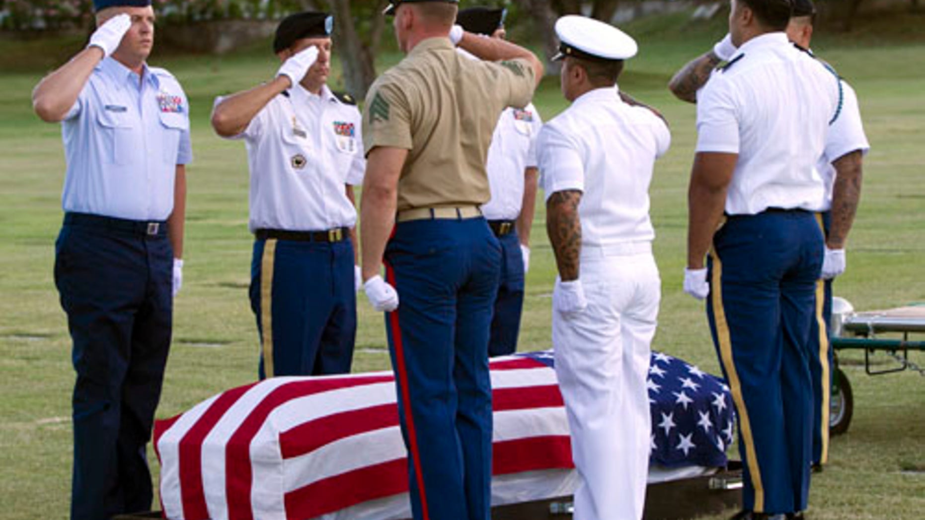 In this photo taken July 27, 2015, in Honolulu, military pallbearers salute over the exhumed remains of unidentified crew members of the USS Oklahoma killed in the Dec. 7, 1941, bombing of Pearl Harbor. The military says it has identified the remains of seven crew members missing since the Oklahoma capsized in the bombing. (AP Photo/Marco Garcia)
