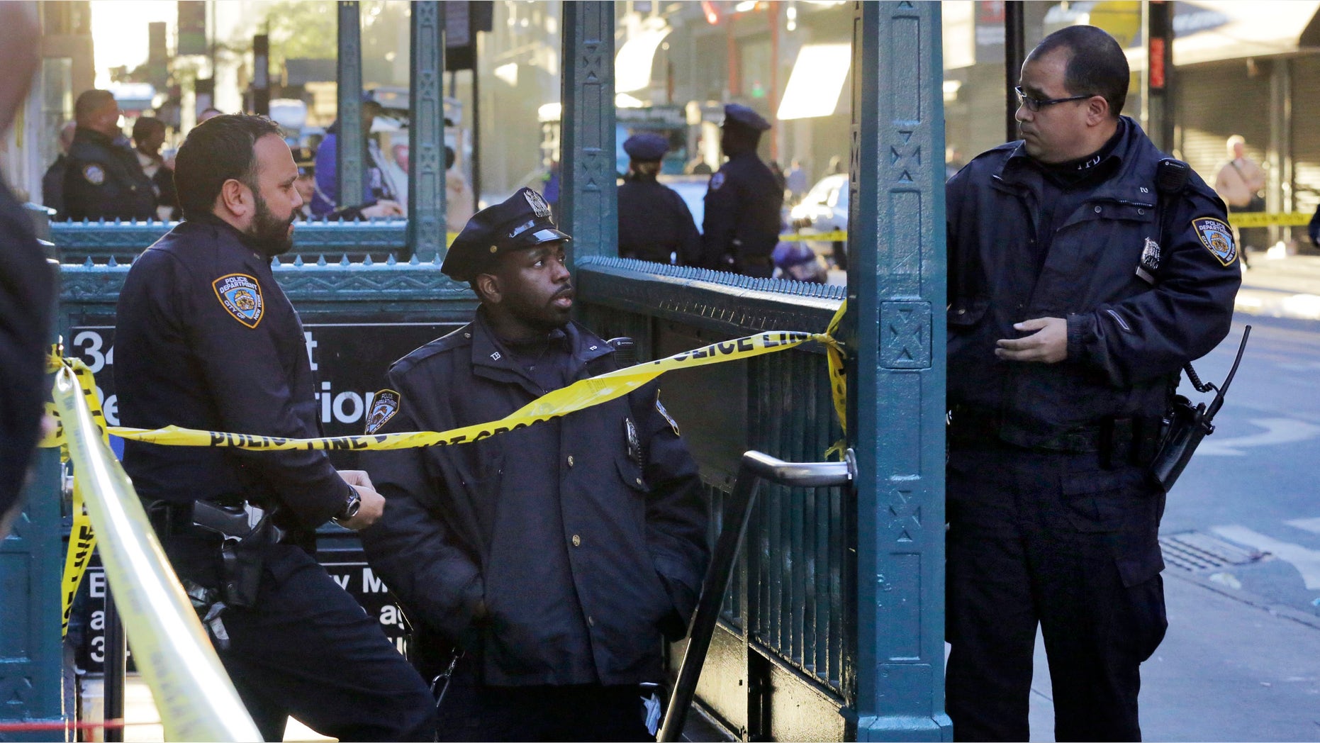 New York Police Department officers investigate a shooting at a subway station entrance at 35th Street and Eighth Avenue, Monday, Nov. 9, 2015, in New York. Authorities said three people have been shot, one fatally. No suspects were immediately arrested. (AP Photo/Mark Lennihan)