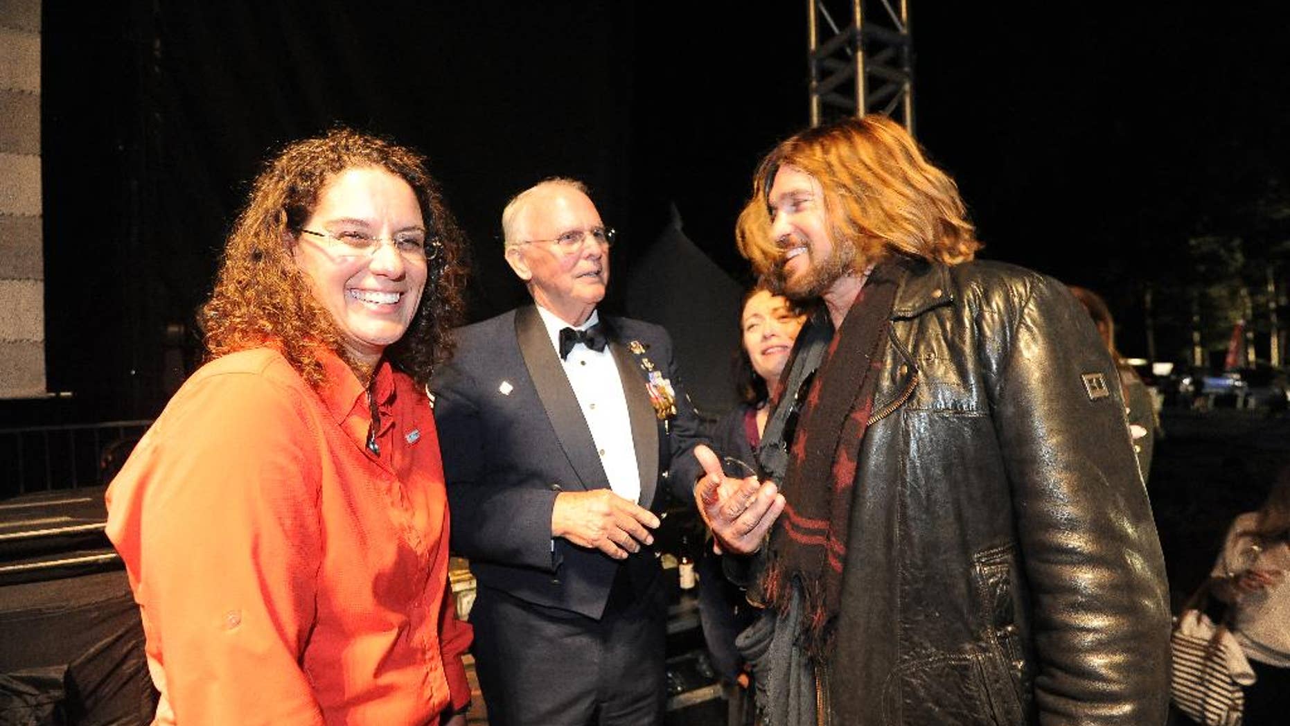 This Saturday, July 5, 2014 photo released by Talbot Photography shows Sharon Landsberry, left, widow of Michael Landsberry, a 45-year-old math teacher who was shot and killed last year at a middle school in the Reno suburb of Sparks, Nev., with country singer Billy Ray Cyrus, right, in Incline Village on Lake Tahoe’s north shore. Cyrus presented a plaque and check to Sharon at a concert on Saturday. Also pictured is retired Air Force Chief Master Sgt. Bob Wheeler, center. (AP Photo/Talbot Photography, Kevin Todd and Chris Talbot)