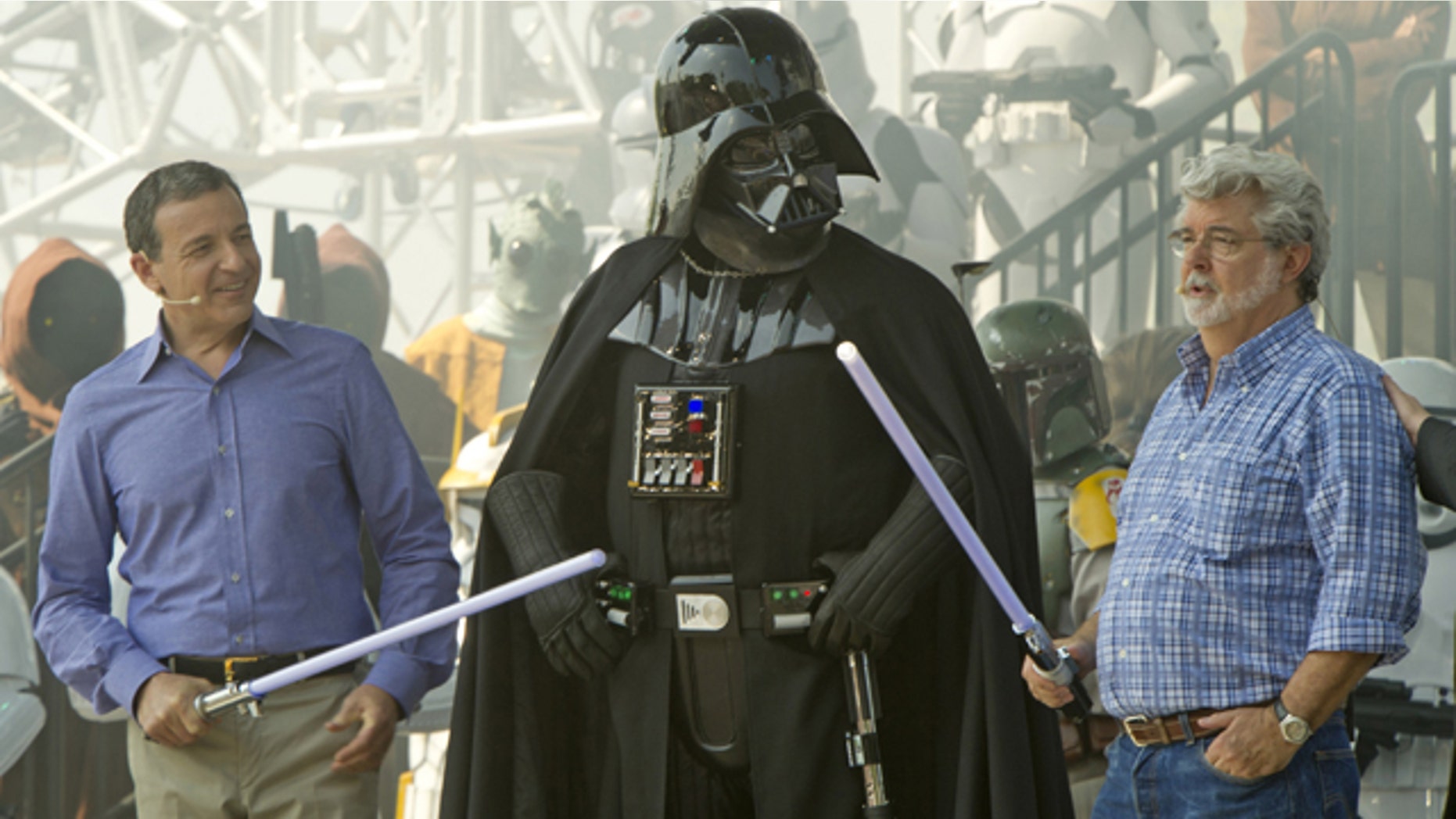 In this publicity image released by Disney, Walt Disney Co. president and CEO Bob Iger, left, and "Star Wars" creator George Lucas, right, flank "Star Wars" character Darth Vadar during grand opening ceremonies for Star Tours - The Adventures Continue, a new 3-D attraction based on the films in Disney's Hollywood Studios theme park in Lake Buena Vista, Fla., Friday, May 20, 2011. (AP Photo/Disney, Kent Phillips)