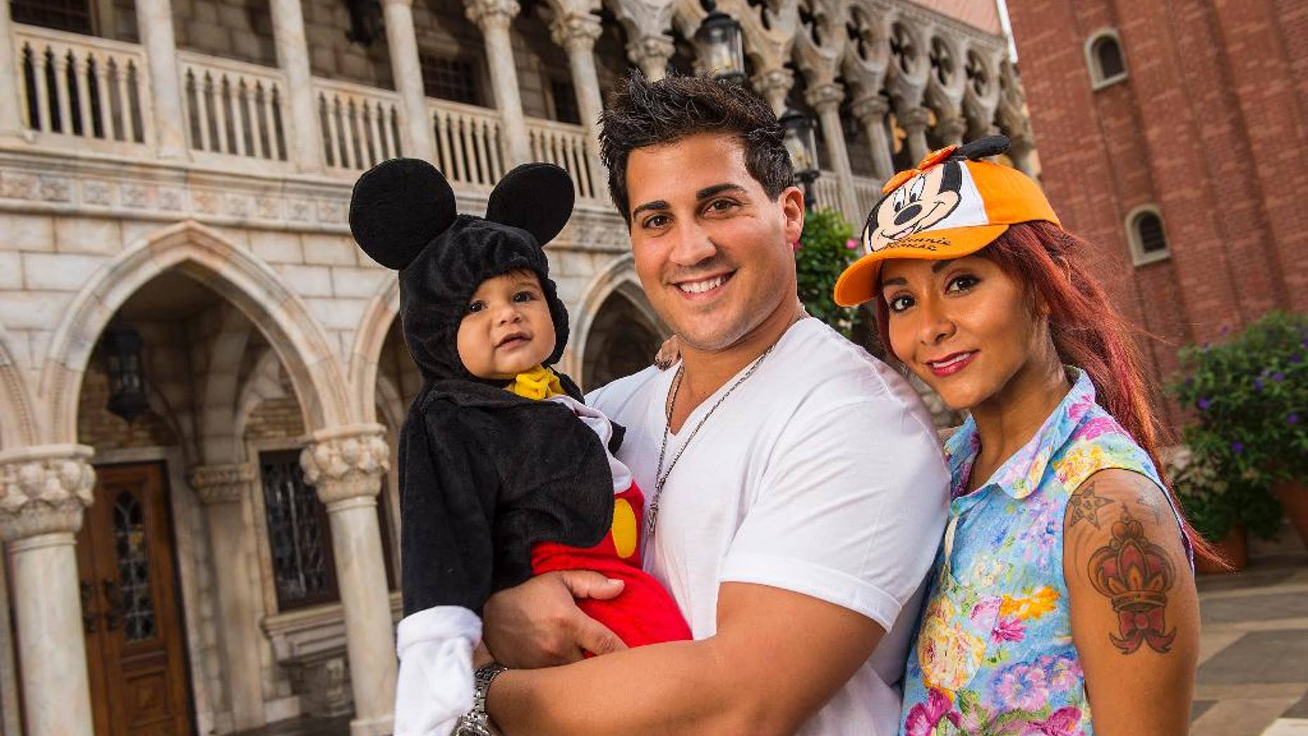 FILE - This image released by Disney shows TV personality Nicole "Snooki" Polizzi, right, from "Jersey Shore," with her fiance Jionni LaValle and their one-year-old son Lorenzo inside the Italy pavilion in the Epcot theme park, in this Sept. 27, 2013 file photo taken at Walt Disney World in Lake Buena Vista, Fla. The cast member of the reality series "Jersey Shore" and "Snooki and JWoww" spinoff intends to marry her fiance Jionni LaValle at the Venetian banquet hall in Garfield in the fall 2014. (AP Photo/Disney, Matt Stroshane, File)