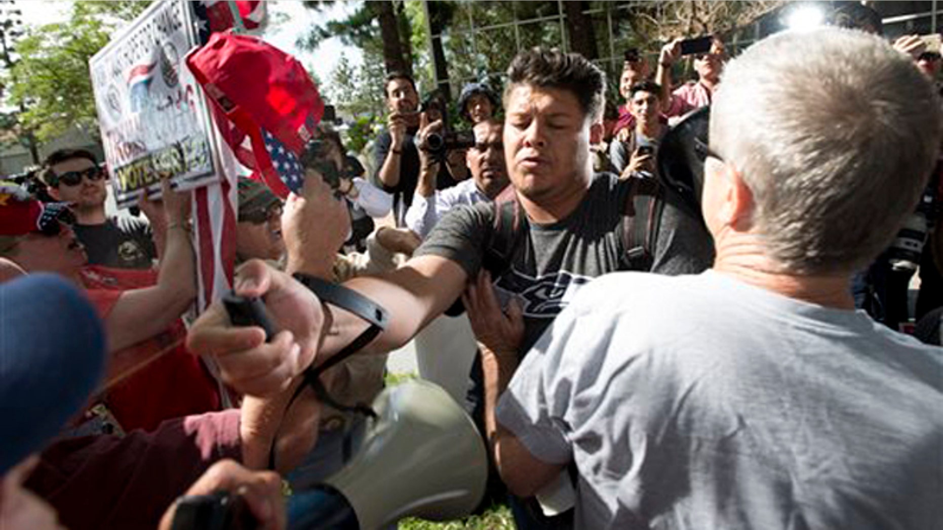 A man, center, sprays Republican presidential candidate Donald Trump supporters with pepper spray during a rally in front of the Anaheim City Hall on Tuesday, April 26, 2016, in Anaheim, Calif. (Leonard Ortiz/The Orange County Register via AP) MAGS OUT; LOS ANGELES TIMES OUT; MANDATORY CREDIT