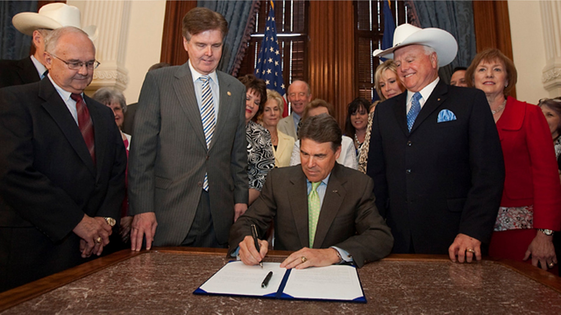 FILE - In this May 24, 2011 photo, Gov. Rick Perry, center, is flanked by state senators and representatives and anti-abortion supporters as he signs the sonogram bill at the state capitol in Austin, Texas.