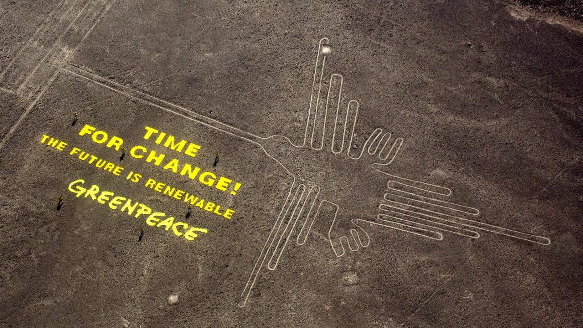 FILE - In this Dec. 8, 2014 file photo, Greenpeace activists stand next to large letters that spell out "Time for Change: The Future is Renewable" next to the hummingbird geoglyph in Nazca, Peru. A Peruvian prosecutor is investigating the suspected involvement of Greenpeace activist Mauro Fernandez in the publicity stunt that allegedly damaged the world-renowned Nazca lines that date to some 1,500 to 2,000 years ago. Authorities have said the fragile site was damaged by footprints. (AP Photo/Rodrigo Abd, File)