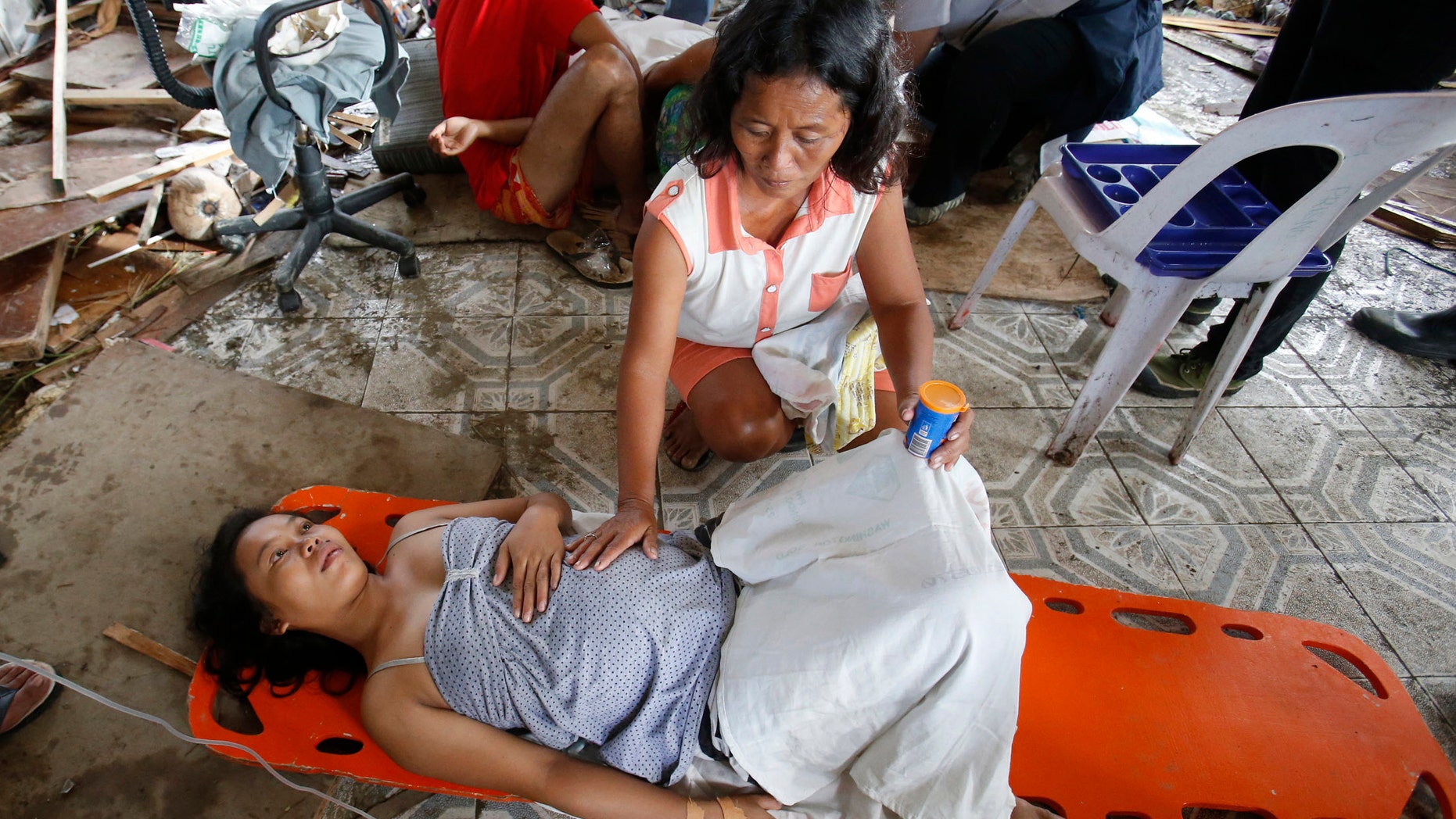 A woman comforts a pregnant relative having labor pains before she delivered a baby at a makeshift birthing clinic in typhoon battered Tacloban city in central Philippines November 11, 2013.