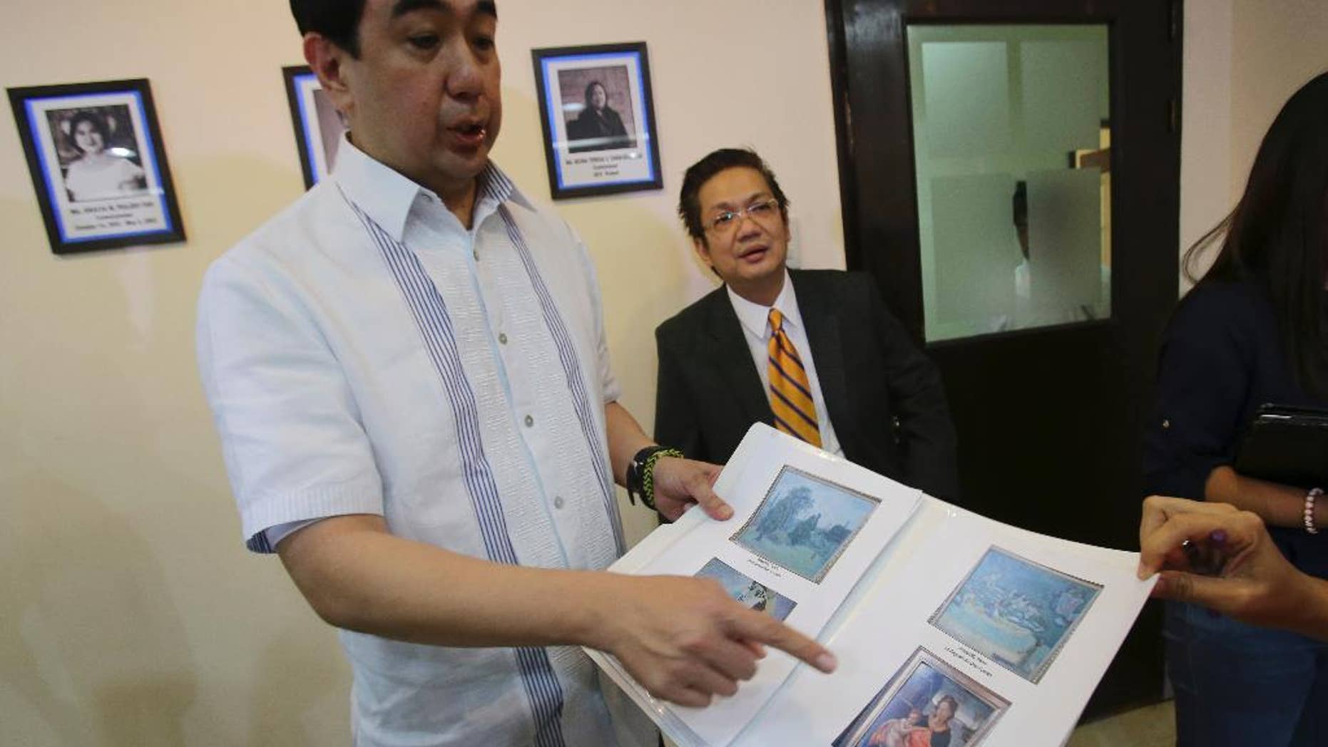 Andres Bautista, head of the Presidential Commission on Good Government, shows reporters some of the rare paintings of European masters that are allegedly part of the collection of the late dictator Ferdinand Marcos as he meets the press in suburban Mandaluyong city, east of Manila, Philippines on Wednesday, Oct. 1, 2014. Bautista says the Philippine government has seized at least 15 paintings from the former home of the Marcos, part of efforts to recover 156 artworks included in his alleged ill-gotten wealth. (AP Photo/Aaron Favila)