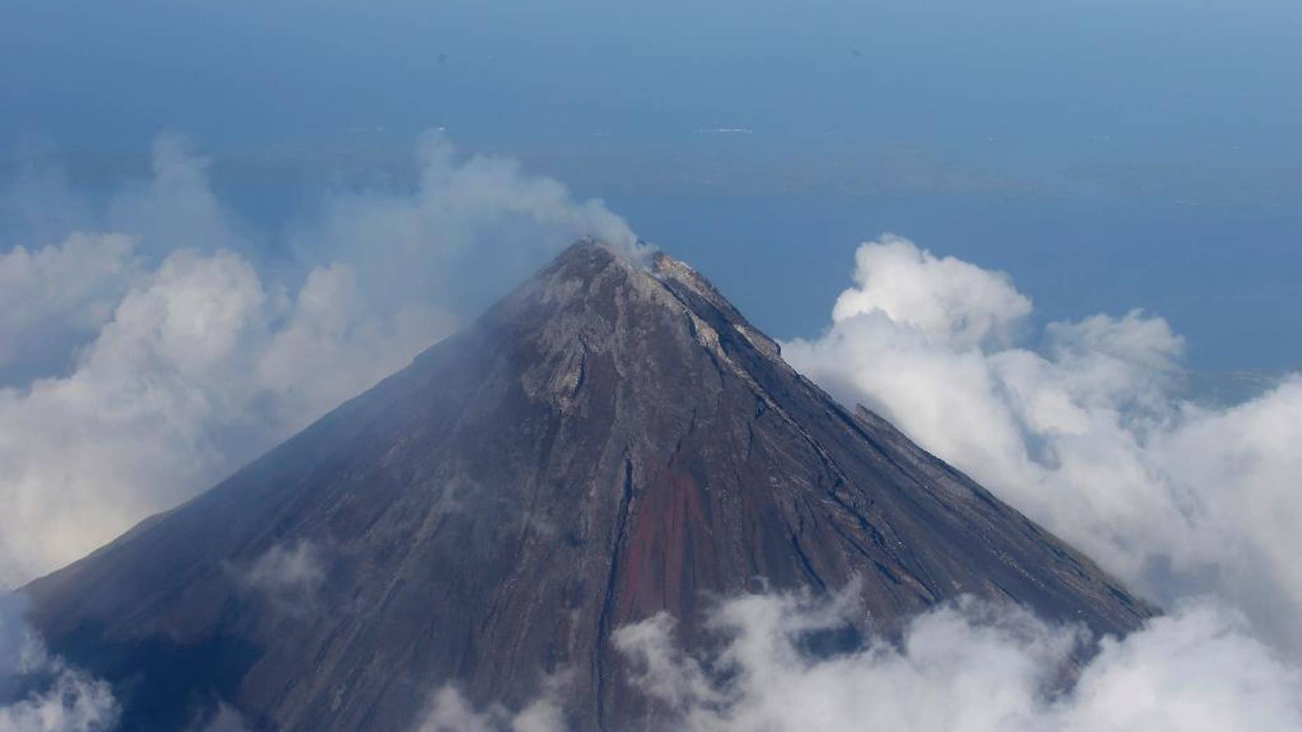 FILE - In this Feb. 26, 2014 file photo, smoke billows from the crater of Mayon volcano, one of the country's most active volcanoes, in Albay province about 550 kilometers southeast of Manila, Philippines. The Philippines' most active volcano has belched out lava fragments as big as a bus that rolled one kilometer (half a mile) down its slope, prompting authorities to start forcibly evacuating thousands of villagers, officials said Tuesday, Sept. 16, 2014. (AP Photo/Bullit Marquez, File)