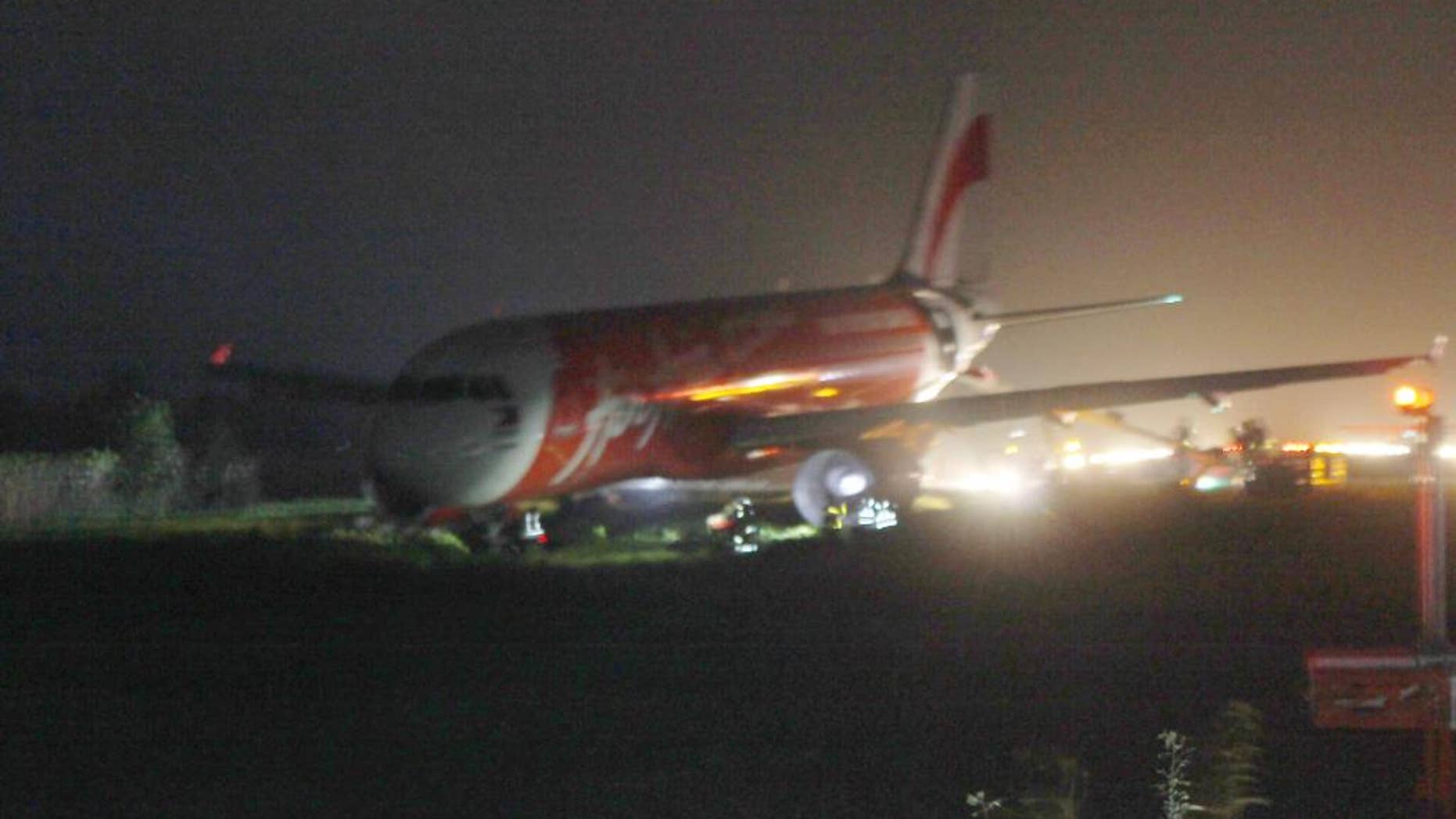 An AirAsia passenger plane sits on the grassy portion of the runway after overshooting upon landing in windy weather at Kalibo airport in Kalibo township, Aklan province in central Philippines Tuesday, Dec. 30, 2014. Giovanni Hontomin, who is in charge of AirAsia Zest's operations, told The Associated Press crewmembers activated an emergency slide to help passengers disembark safely from the Airbus aircraft. There were no immediate reports of injuries to the passengers and crew and the plane remained stuck on a grassy area near the runway’s end. (AP Photo/Jun Aguirre)