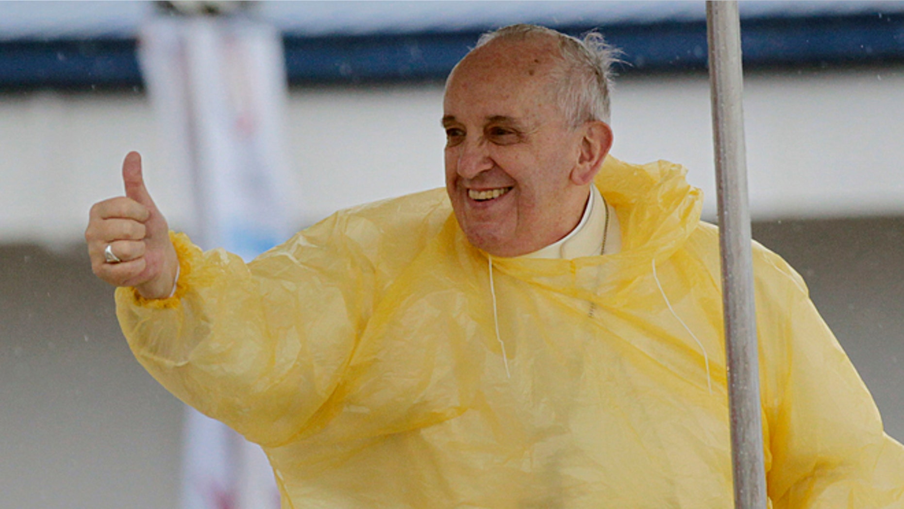 Wearing a yellow raincoat, Pope Francis gives a thumbs up to the faithful as he arrives in Tacloban, Philippines, Saturday, Jan. 17, 2015. A rain-drenched but lively crowd wearing yellow and white raincoats welcomed Pope Francis in the typhoon-ravage central Philippine city of Tacloban early Saturday, chanting "Papa Francesco, Viva il Papa!" (AP Photo/Wally Santana)