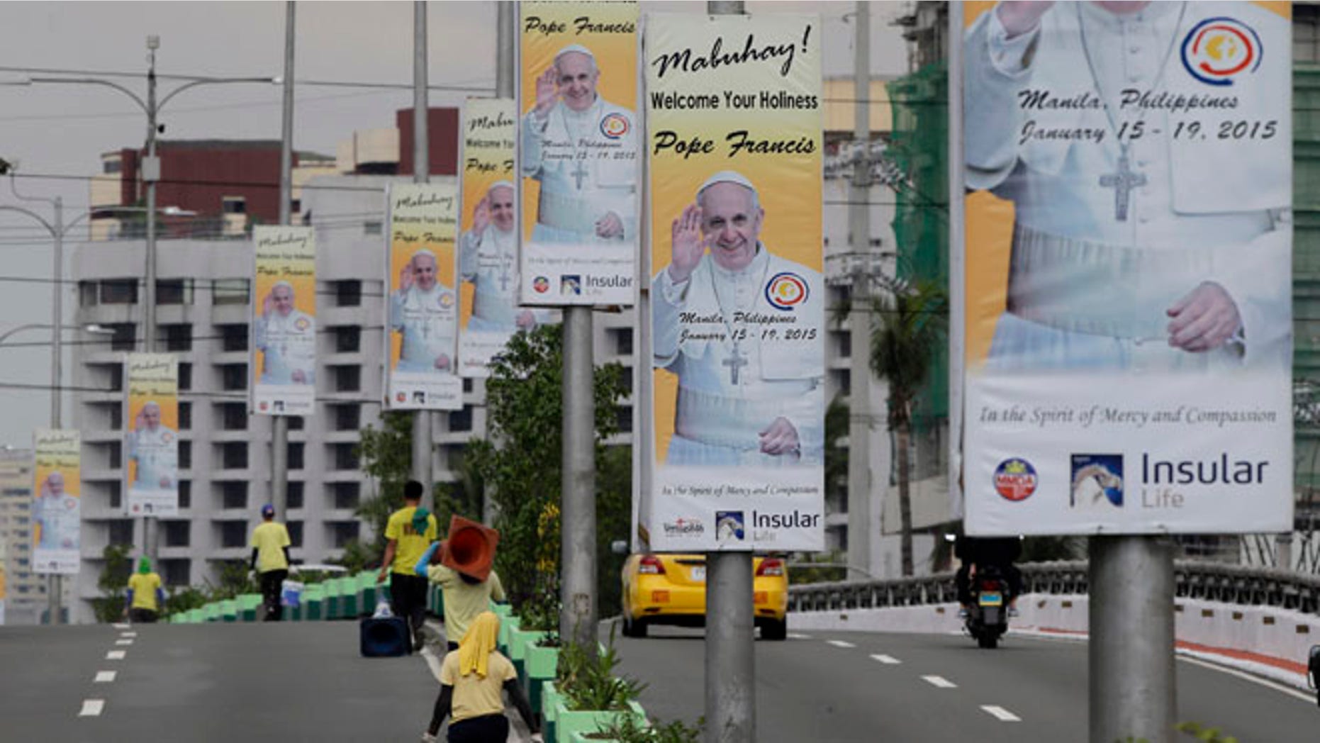 Jan. 3, 2015: Workers spruce up an avenue in Manila, Philippines, in preparation for a five-day visit of Pope Francis. (AP)