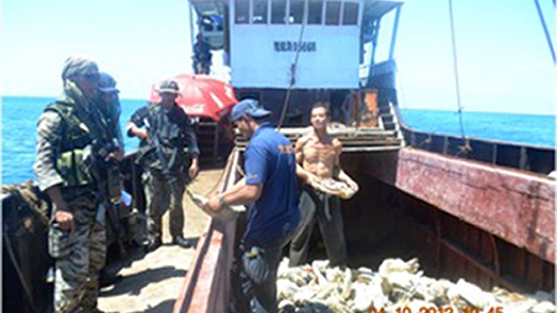 April 10, 2012: In this photo released by the Philippine Navy, Filipino naval personnel look at giant clam shells on board a Chinese fishing vessel at the disputed Scarborough Shoal in the South China Sea, near the Philippines.