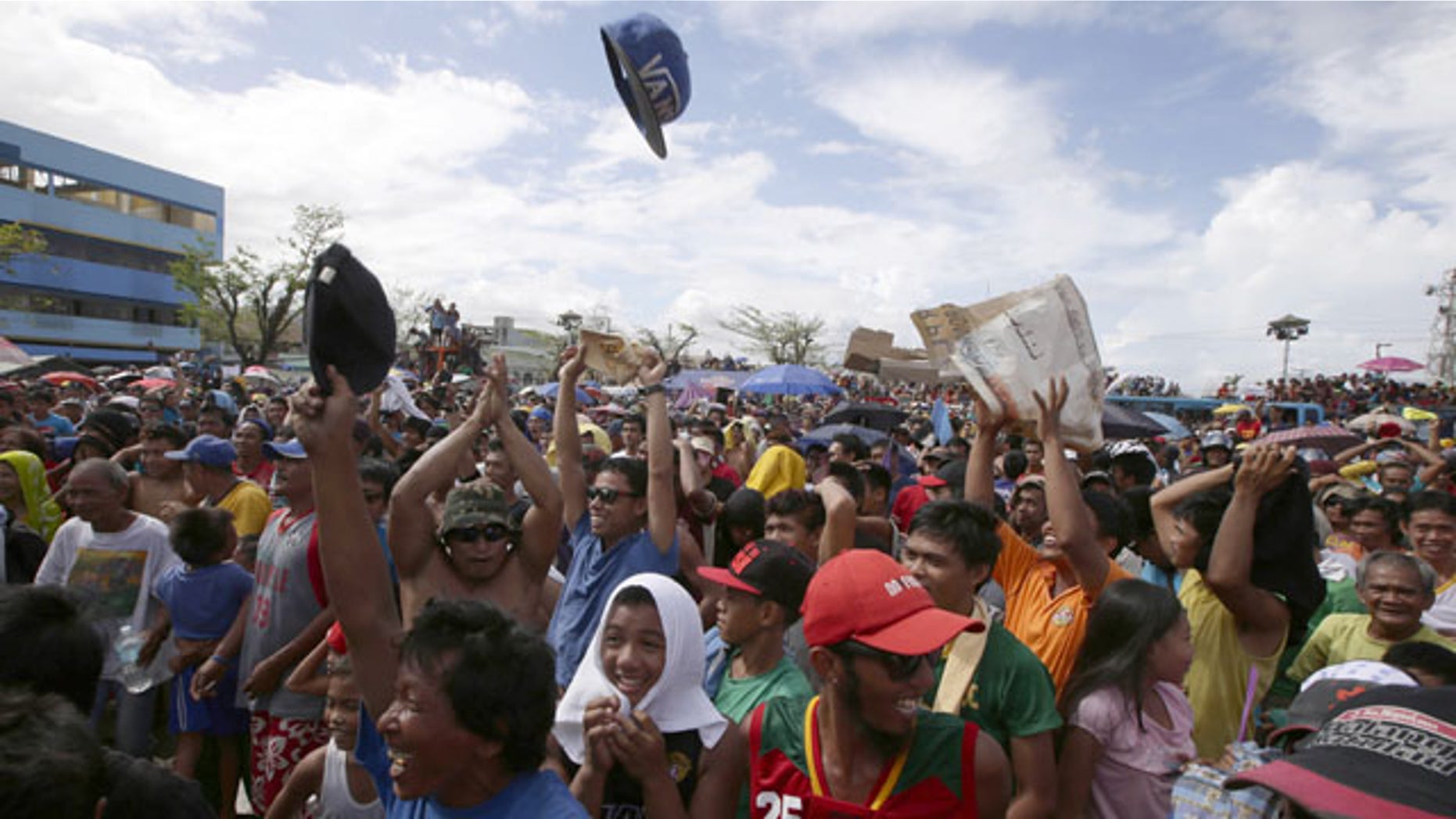 November 24, 2013: Typhoon survivors throw their caps in the air following an announcement of Filipino boxer Manny Pacquiao's win by a unanimous decision over American Brandon Rios in their WBO international welterweight boxing title match in Macau, which was telecast live at a public park in Tacloban. (AP Photo)