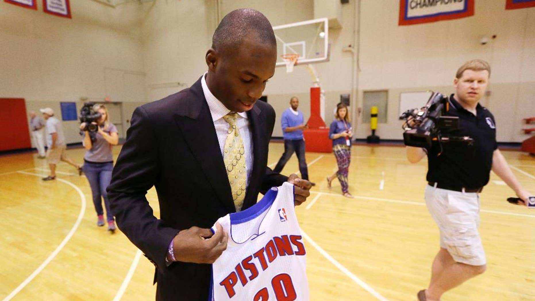 Detroit Pistons guard Jodie Meeks is followed by the media as he holds his new jersey at the team's practice facility in Auburn Hills, Mich., Monday, July 14, 2014. The Pistons hope he can provide some much-needed perimeter shooting this season under new coach Stan Van Gundy. (AP Photo/Carlos Osorio)