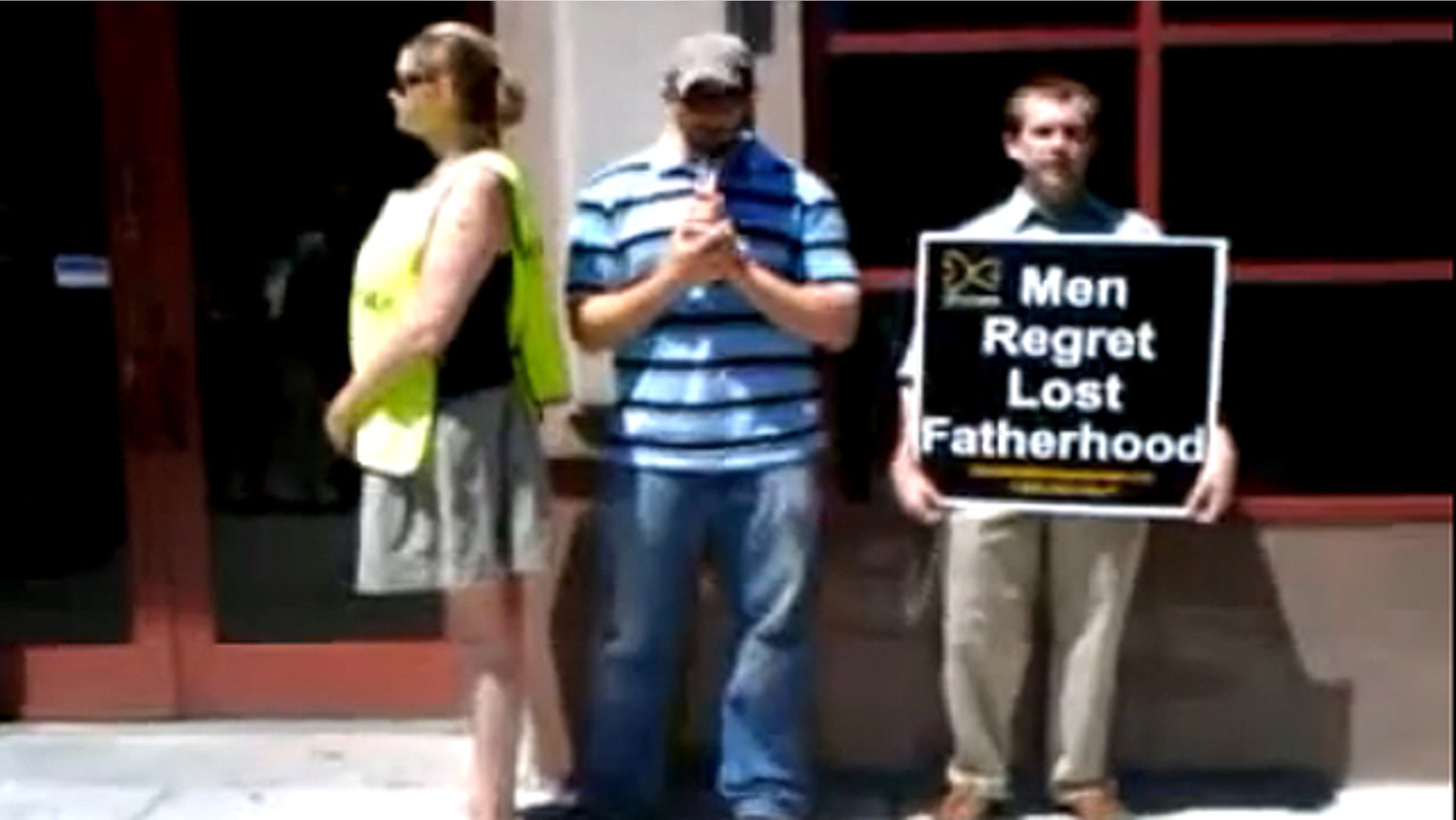 Complaining witness, left, stands next to Joe Holland, middle, as he prays the rosary outside Planned Parenthood's Near North Center in Chicago.