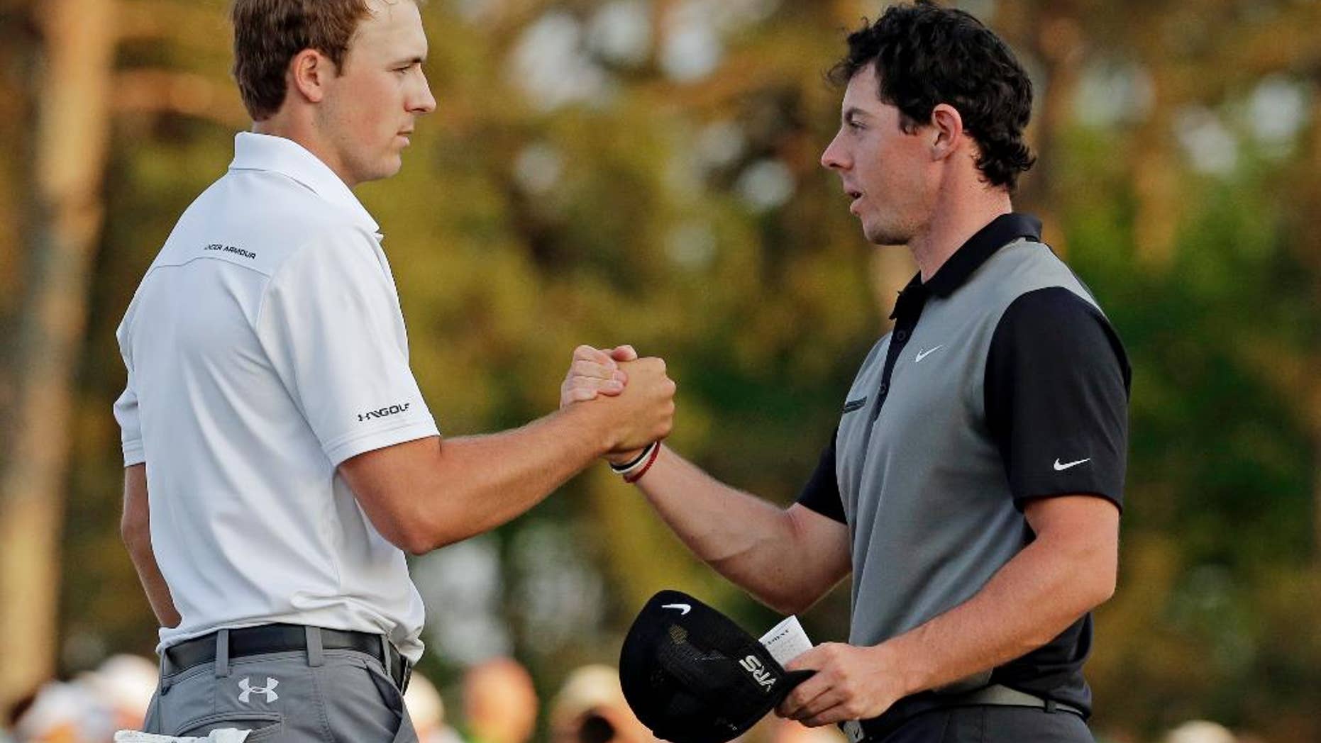 FILE - In this April 11, 2014, file photo, Jordan Spieth, left, shakes hands with Rory McIlroy, of Northern Ireland, on the 18th green following the second round of the Masters golf tournament in Augusta, Ga. The match that didn't happen in San Francisco will be available in stroke play at The Players Championship this week. Match Play winner Rory McIlroy, ranked No. 1, and Masters champion Jordan Spieth, ranked No. 2, are in the same group for the opening two rounds.(AP Photo/Charlie Riedel, File)