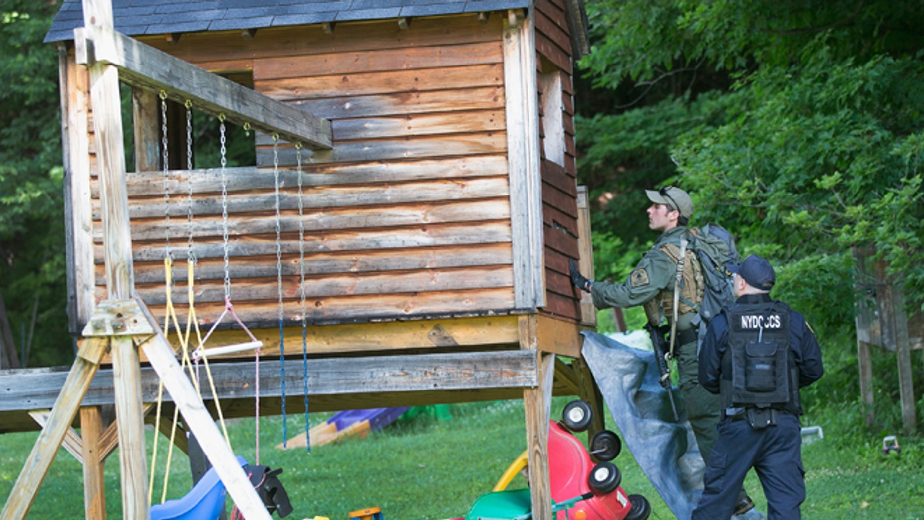 Law enforcement personnel search a child's playhouse as the manhunt for convicted murderers, Richard Matt and David Sweat, on June 26, 2015 in Chasm Falls, New York. (Photo by Scott Olson/Getty Images)