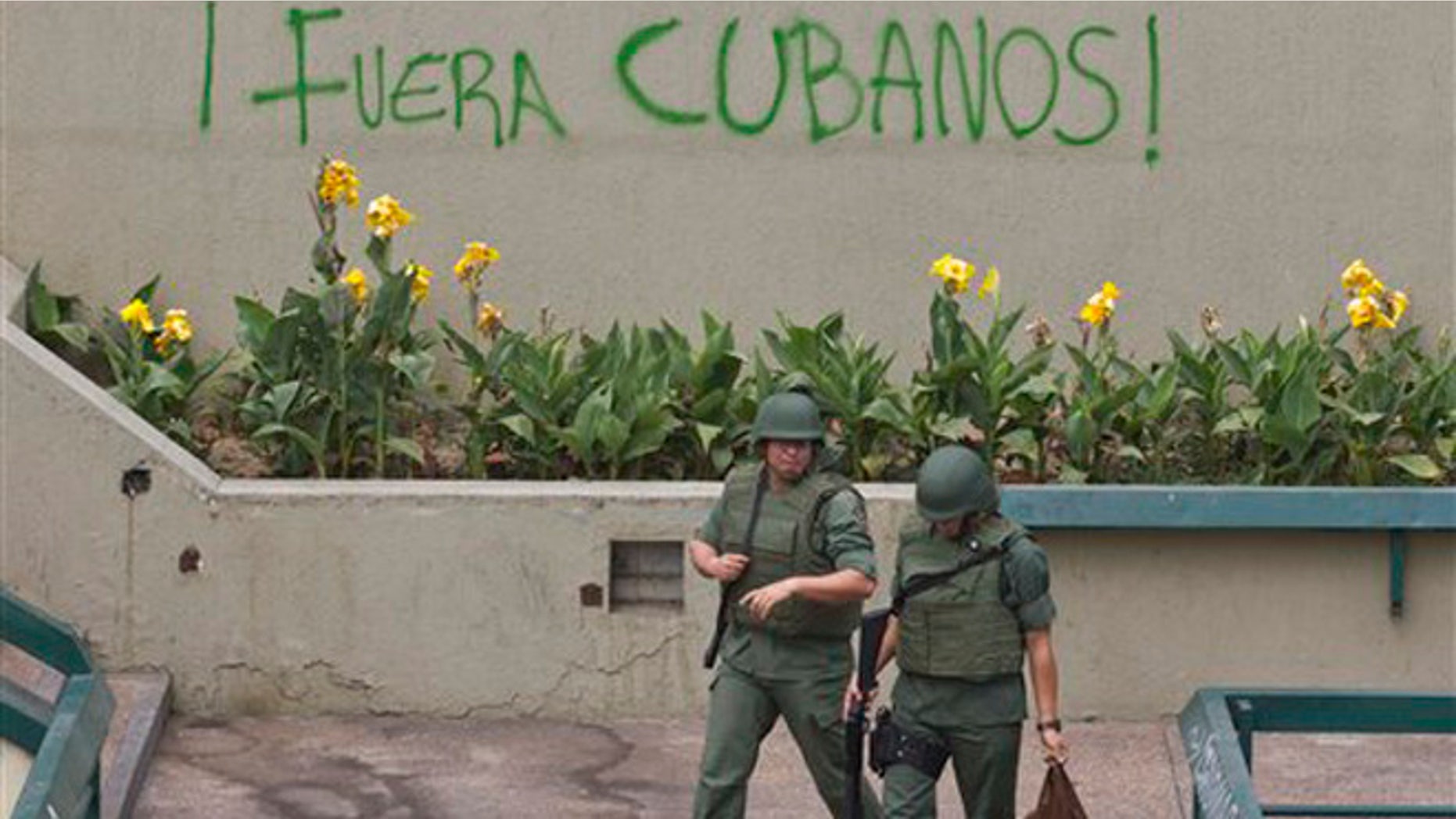 Bolivarian National Guard officers patrol Plaza Altamira after taking control of it, in Caracas, Venezuela, Monday, March 17, 2014. Government security forces took control of a Caracas plaza and surrounding neighborhoods Monday morning that had become the center of student-led protests. The graffiti on the wall reads in Spanish "Cubans Out!". Clusters of National Guardsmen were a visible presence not only on Plaza Altamira, but along the principal streets extending from it in the municipality of Chacao.