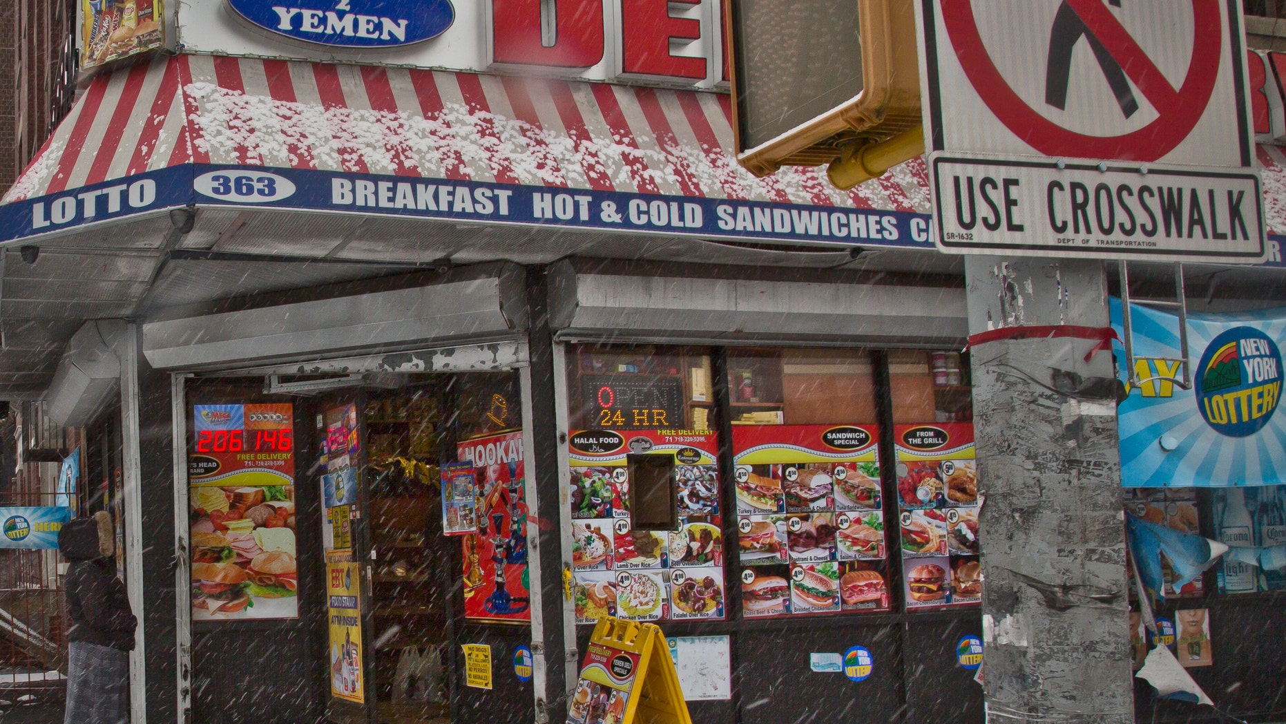 A woman approaches a New York City deli, Tuesday, Jan. 6, 2015, where a robbery occurred the night before.