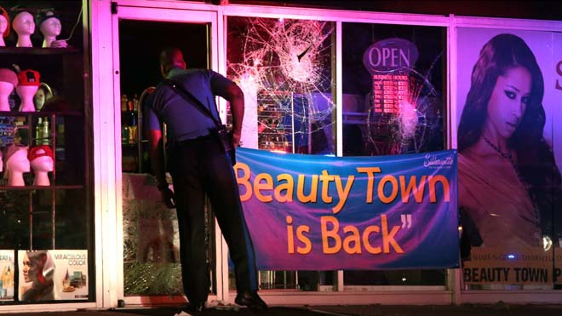 Sept. 23, 2014: A Missouri Highway Patrol trooper looks inside the vandalized Beauty Town store on West Florissant Avenue in Ferguson. (AP Photo/St. Louis Post-Dispatch)