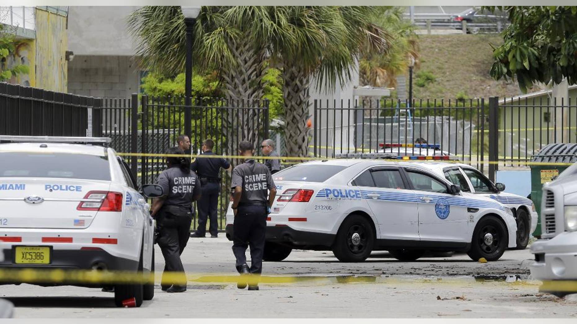 Miami Police officers at the scene where a man holding a pipe has been shot by a Miami police officer in a downtown park ,Thursday, June 11, 2015, in Miami. The man’s condition and identity were not immediately available. He was taken to a local hospital for treatment. (AP Photo/Alan Diaz)