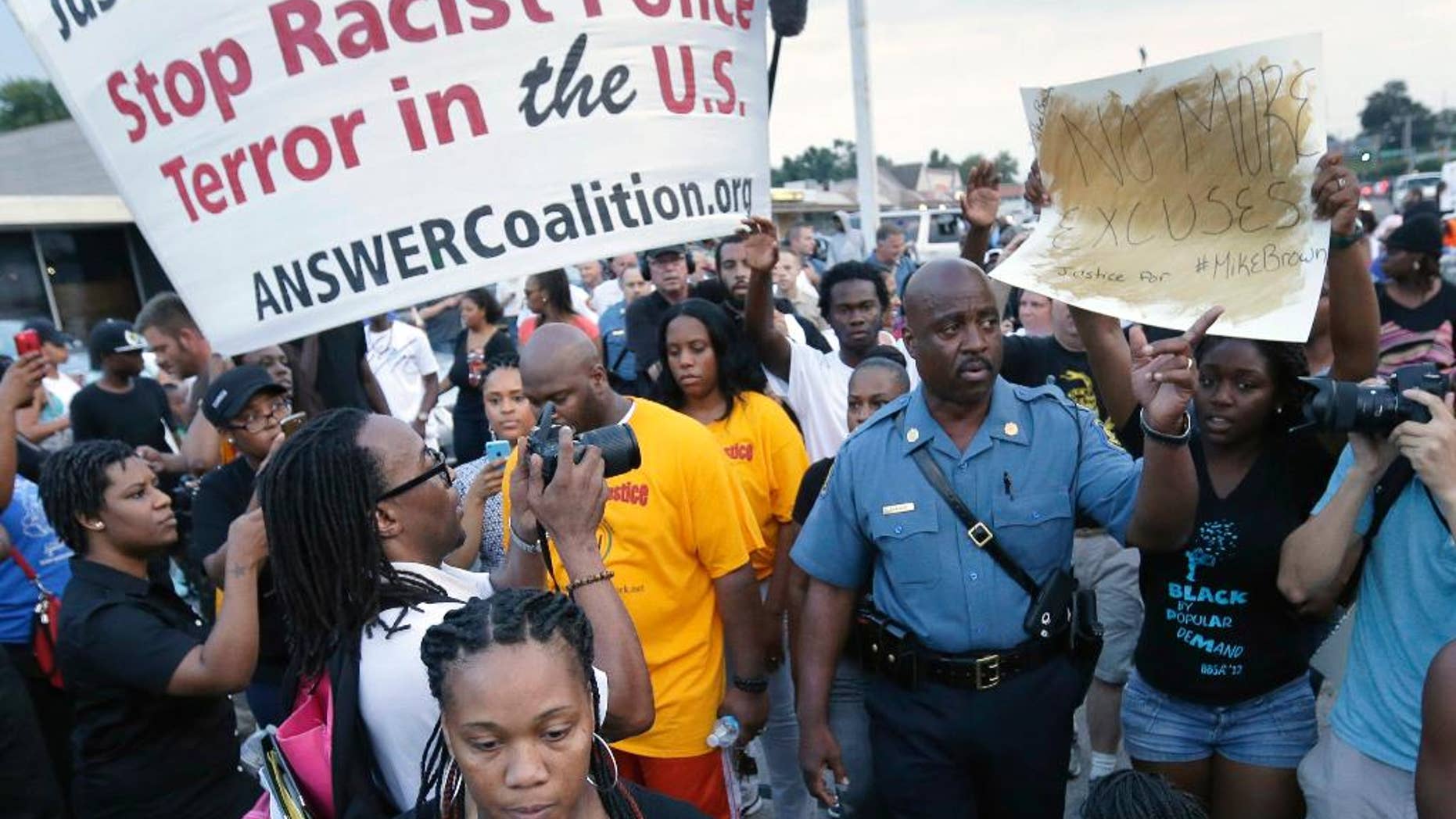 FILE - In this Aug, 16, 2014 file photo Missouri Highway Patrol Capt. Ron Johnson, center right, walks among people protesting the police shooting death of Michael Brown in Ferguson, Mo. Emails sent to top public-safety officials both criticizing and praising Johnson for appearing to sympathize with protesters illustrate one of the challenges that authorities could face after a grand jury decides whether to charge the police officer who killed Brown _ how to walk a fine line between providing public empathy and security. (AP Photo/Charlie Riedel, File)