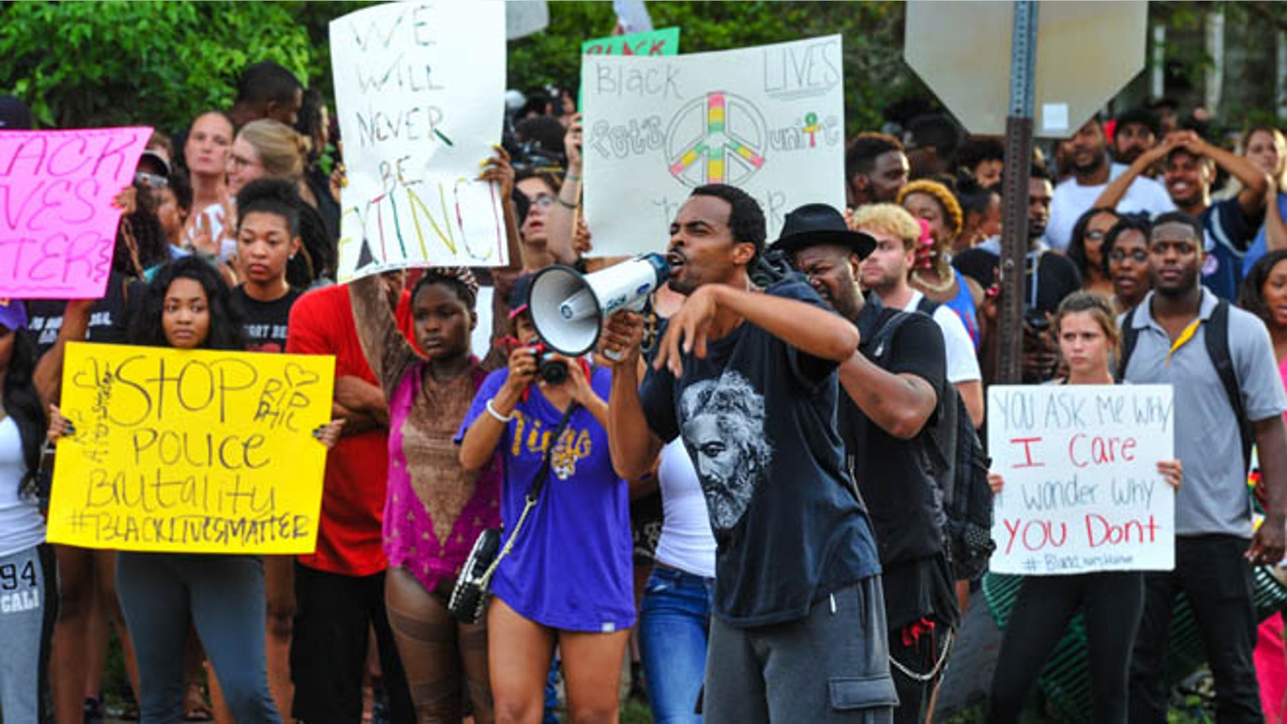A man speaks as a group of protesters gather against another group of protesters, while authorities watch in Baton Rouge, La., Sunday, July 10, 2016. Police officers responded to reports that protesters were en route to block Interstate 10 and prevent another group of protesters from marching. (Scott Clause/The Daily Advertiser via AP)