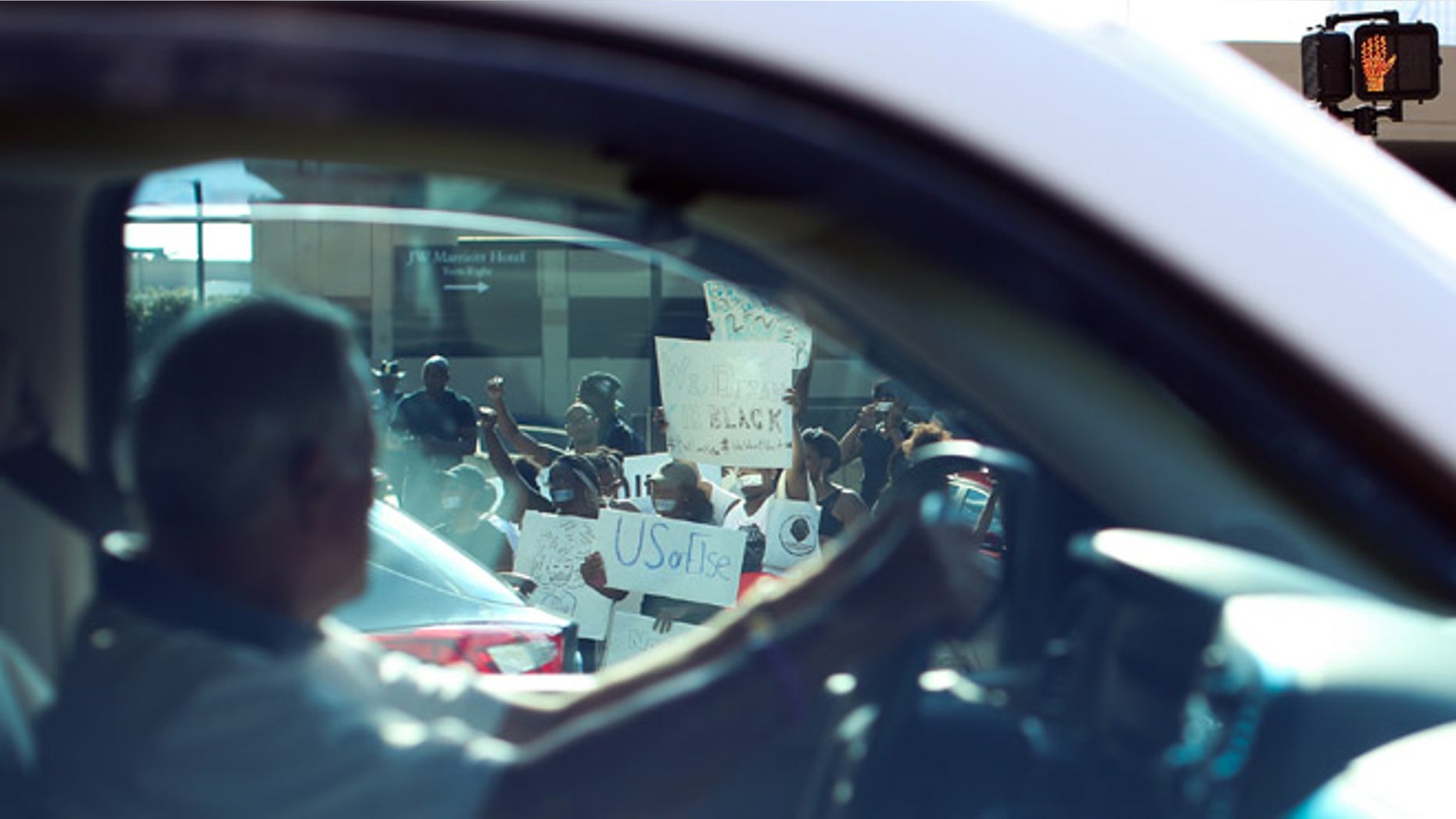 A driver passes demonstrators as they block an entrance to Lenox Square Mall during a Black Lives Matter protest in Atlanta, Saturday, Sept. 24, 2016, in response to the police shooting deaths of Terence Crutcher in Tulsa, Okla. and Keith Lamont Scott in Charlotte, N.C. The Black Lives Matter chapter of Atlanta is boycotting major retailers following the recent police shooting deaths involving black men. (AP Photo/Branden Camp)