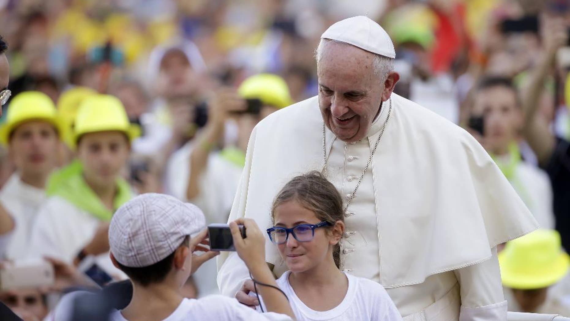 FILE - In this Tuesday, Aug. 4, 2015, file photo, Pope Francis poses for a photo as he arrives in St. Peter's Square at the Vatican for an audience with with Altar boys and girls. Francis thrills Democrats with his teachings on climate change, social justice and immigration. At the same time, his message on life and the Catholic Church's traditional opposition to abortion comfort Republicans. Both Democrats and Republicans are looking forward to Francis' remarks to Congress next month. (AP Photo/Gregorio Borgia, File)