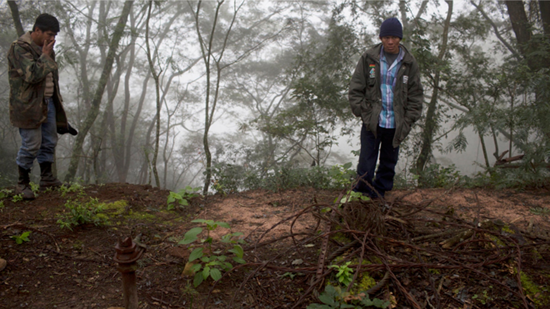 In this June 25, 2015 photo, Guarani environmental health specialist Albino Flores, right, and farmer David Benitez stand at the site of an unsealed oil well, left behind by the state-owned YPFB oil company inside Aguarague National Park in southeastern Bolivia. Benitez, who lives in the park and grazes his cattle among the wells, said the odor is much stronger in the summer, when theres no water to wash the oil downstream. (AP Photo/Juan Karita)