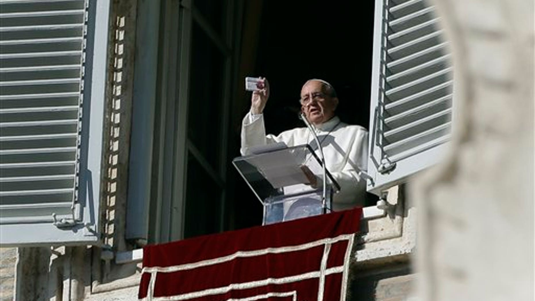 Pope Francis shows a rosary in a box designed to resemble a packets of pills, during his traditional Sunday's appearance from his studio overlooking St. Peter's Square at the Vatican, Sunday, Nov. 17, 2013. Joking that he's like a pharmacist, Pope Francis is promoting prayer as medicine for the heart. (AP Photo/Gregorio Borgia)