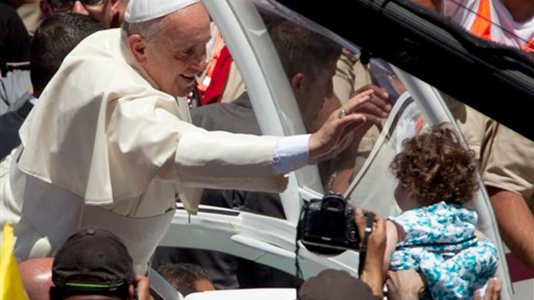 May 25, 2014: Pope Francis reaches to a girl after a mass in Bethlehem, West Bank. (AP)