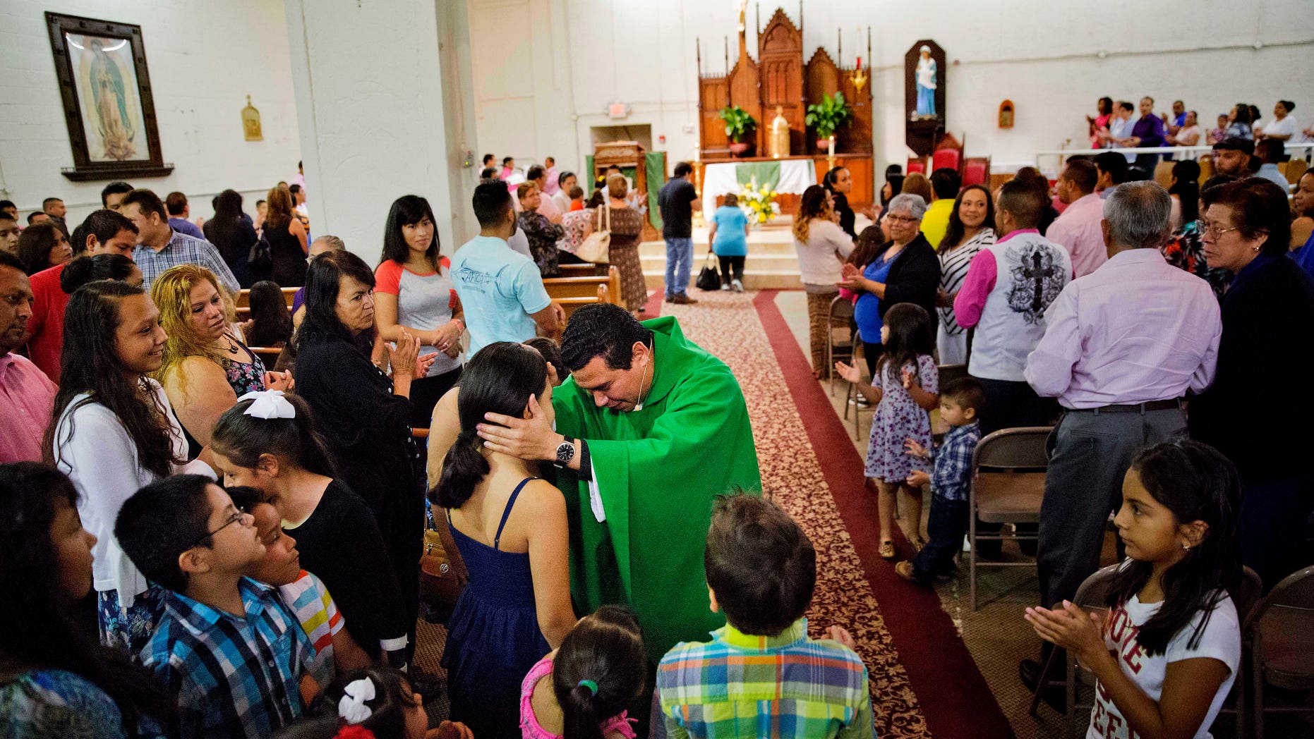 The Rev. William Canales greets parishioners during Mass at St. John Paul II Pastoral Center in Gainesville, Ga., on Sunday, Aug. 9, 2015. Canales noted the pope's exhortation for priests to be close to the marginalized and be "shepherds living with the smell of the sheep." Canales joked, "I smell like the chicken here." (AP Photo/David Goldman)