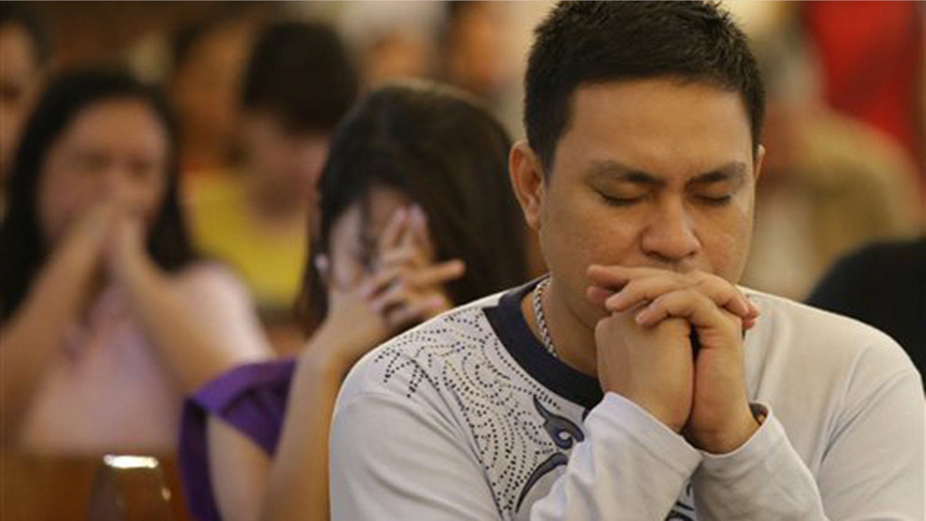 CORRECTS MONTH- Filipino Catholics pray during a mass at the Our Lady of Remedies Parish Church in Manila, Philippines Sunday, Sept. 22, 2013. Catholics around the globe are expressing mixed but mostly positive reactions to Pope Francis' recent remarks that the church has become too focused on "small minded rules" on hot-button issues like homosexuality and abortion. (AP Photo/Aaron Favila)