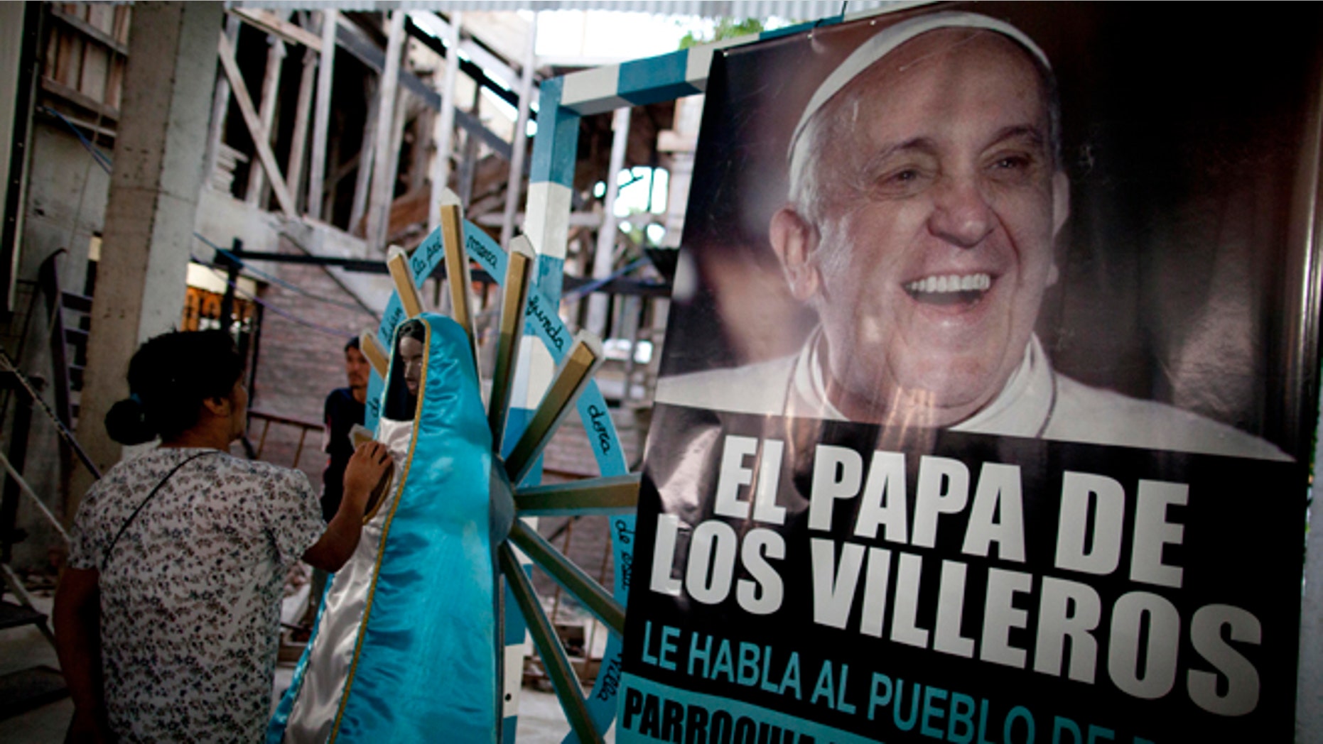 A woman touches a religious figure beside a banner of Pope Francis reading in Spanish, "The Pope of the people of the slum" as she attends a mass in his honor at the 1-11-14 slum's church in Buenos Aires, Argentina, Thursday, March 13, 2014. On the day of the first anniversary of the Pope's election, people from the 1-11-14 slum gather at their church to watch an interview that Pope Francis gave recently from his residence at the Vatican to FM Bajo Flores, a community radio station that broadcasts from the slum. (AP Photo/Natacha Pisarenko)