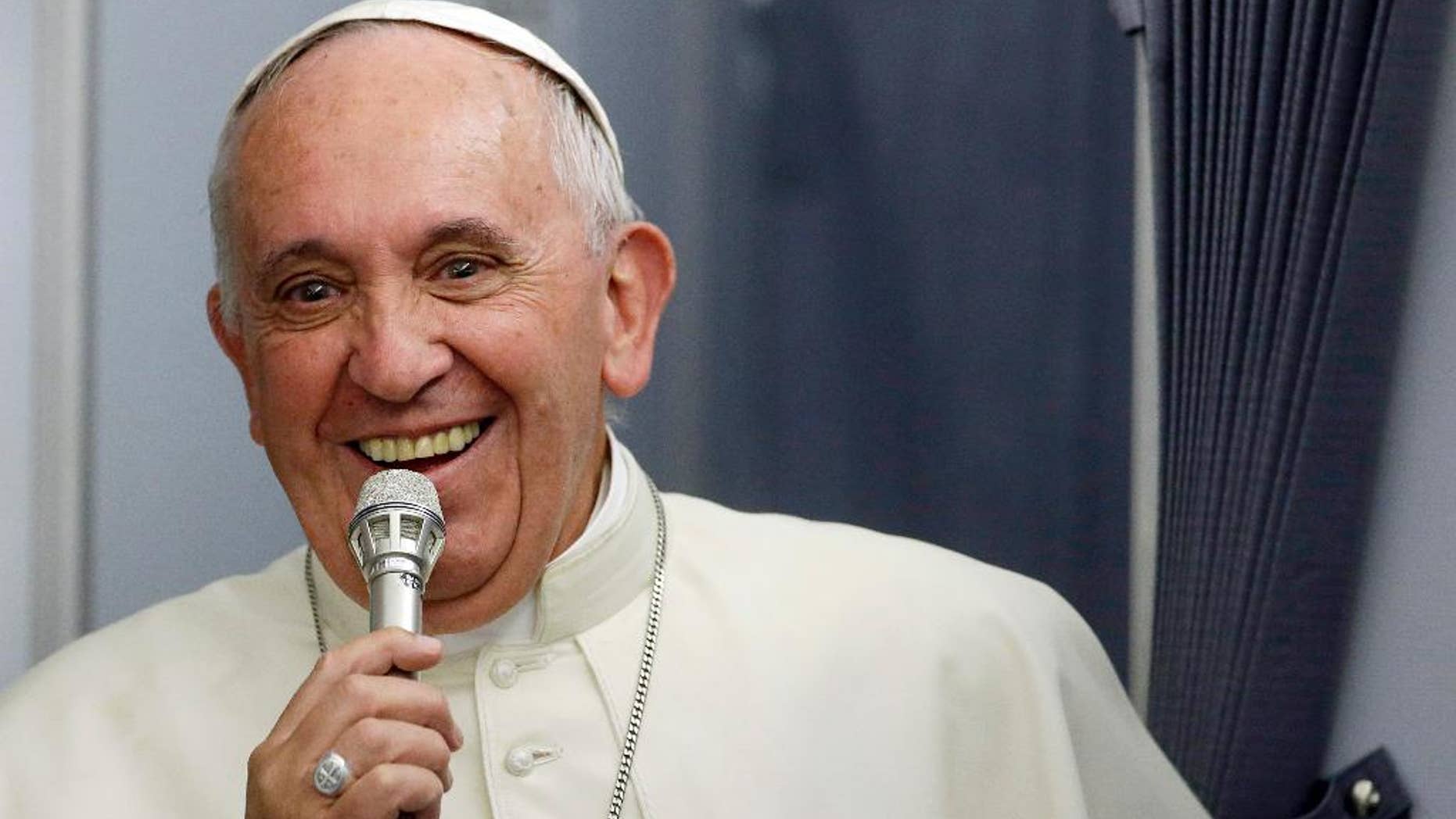 In this photo taken on Sunday, July 12, 2015, Pope Francis smiles as he meets the media during an airborne press conference aboard the airplane directed to Rome, at the end of his Apostolic journey in Ecuador, Bolivia and Paraguay. (AP Photo/Gregorio Borgia)