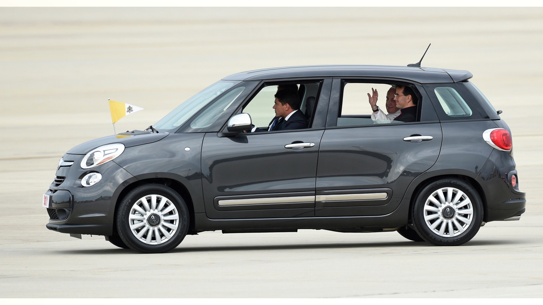 FILE - In this Sept. 22, 2015, file photo, Pope Francis waves from inside a Fiat 500 as he departs Andrews Air Force Base in Md. One of the two Fiats used by Pope Francis during this visit to Philadelphia last year is going up for auction. The car will be up for bid as part of the Philadelphia Auto Show black tie gala on Jan. 29. Bids will be accepted in person and online. (AP Photo/Susan Walsh, File)