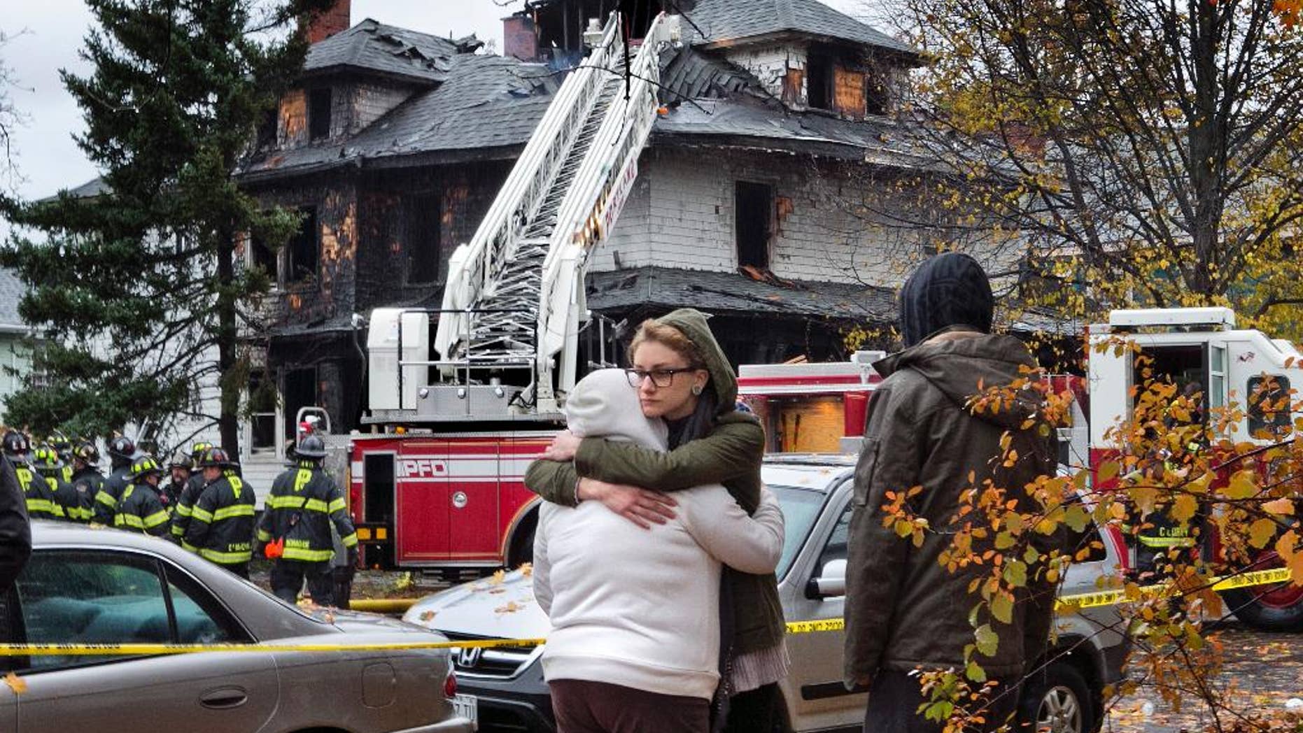 FILE - In this Nov. 1, 2014, file photo, friends of a victim of a fatal apartment building fire console one another other in Portland, Maine. The owner of an apartment house where six people died in a fire that started hours after a Halloween party has been indicted on six counts of manslaughter, authorities announced on Friday, July 10, 2015. (AP Photo/Robert F. Bukaty, File)