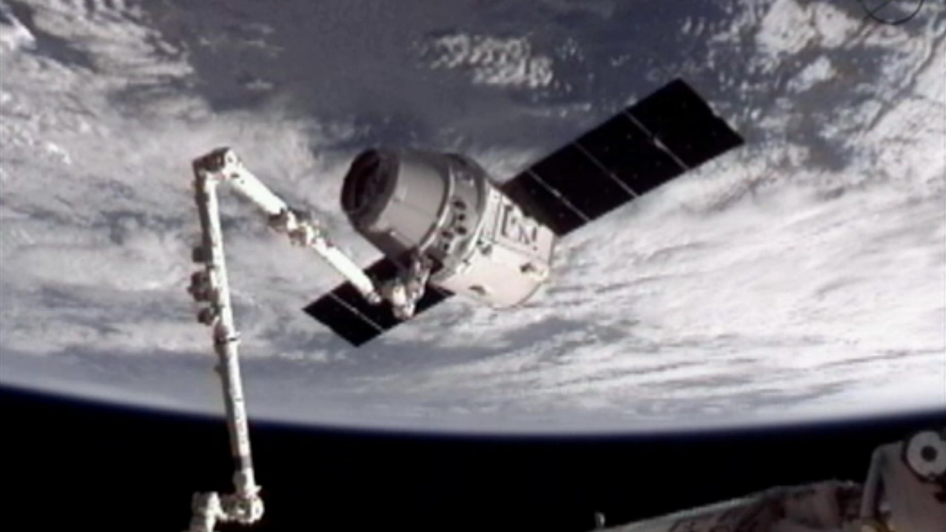 May 25, 2012: This image provided by NASA-TV shows the SpaceX Dragon commercial cargo craft, top, after Dragon was grappled by the Canadarm2 robotic arm and connected to the International Space Station.