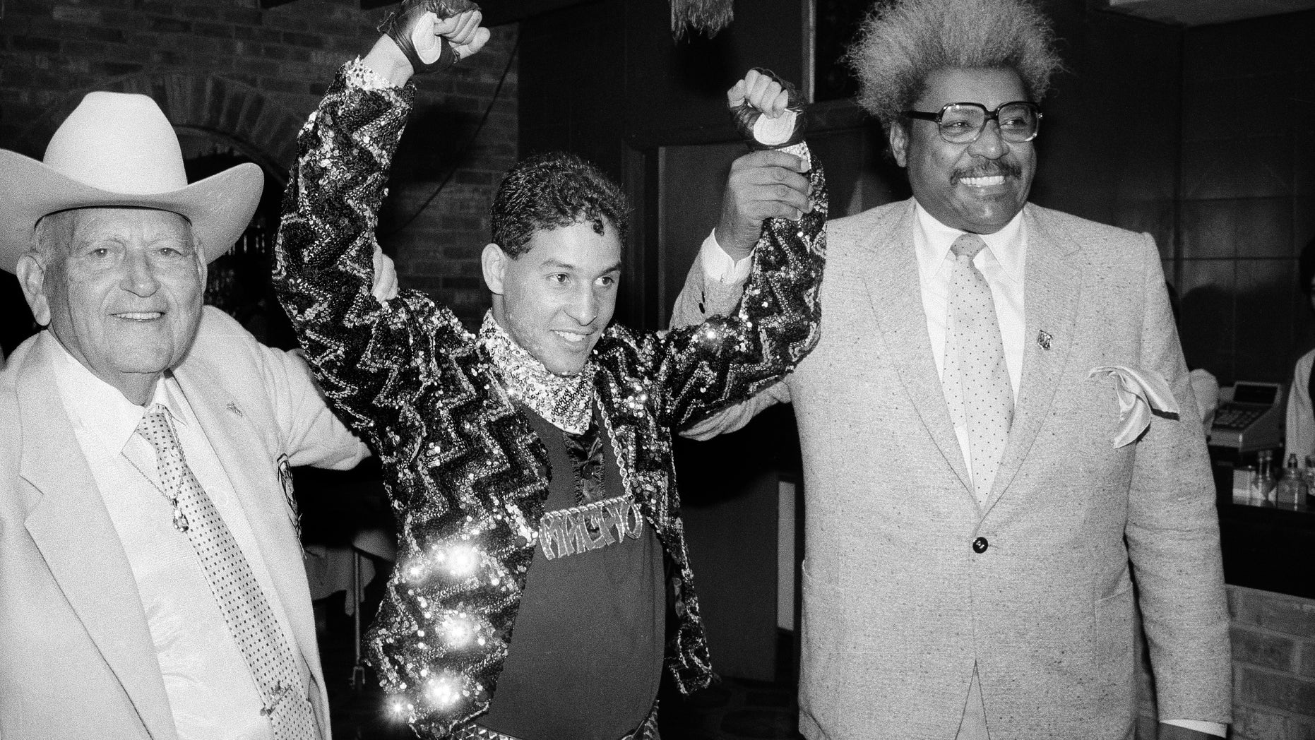 In this Dec. 9, 1986 file photo, Hector "Macho" Camacho WBC lightweight boxing champion, is escorted by Marty Cohen, left, and boxing promoter Don King, right, during a news conference in New York.
