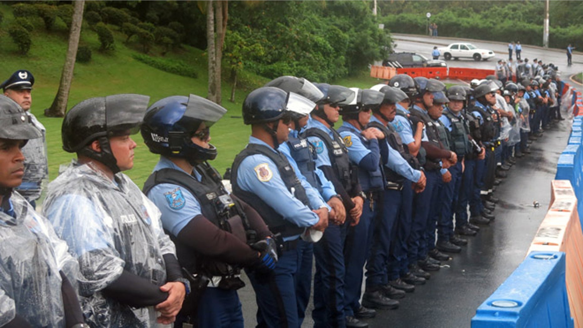 Police officers form a barrier against Puerto Ricans protesting the creation of a federal control board in Fajardo, Puerto Rico, Friday, Nov. 18, 2016. The board is charged with overseeing Puerto Rico's finances amid a dire economic crisis and is meeting for the first time in the U.S. territory. (AP Photo/Danica Coto)